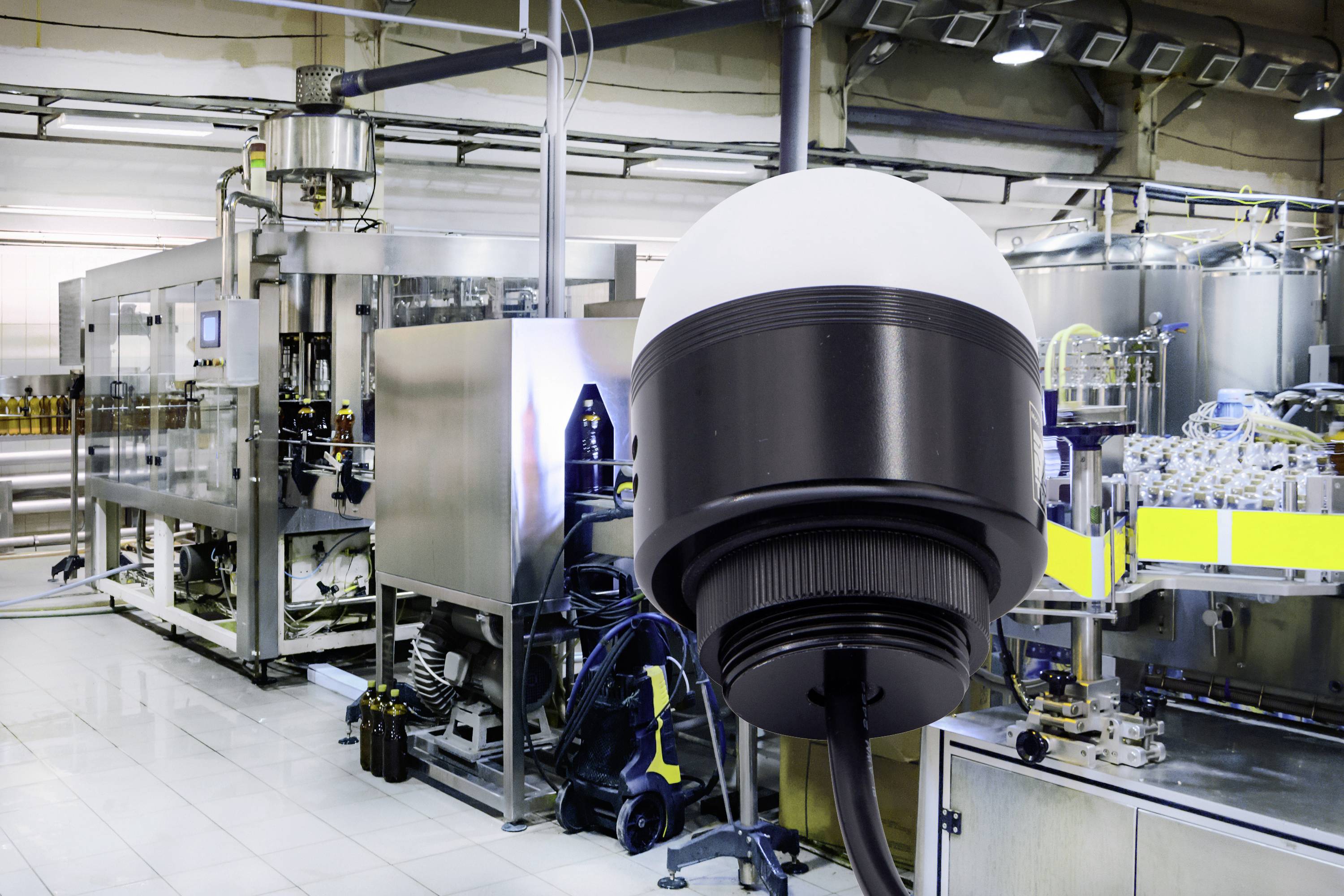 Überwachungskamera in einer industriellen Produktionshalle. Im Hintergrund sind Maschinen und Produktionsausrüstung zu sehen.