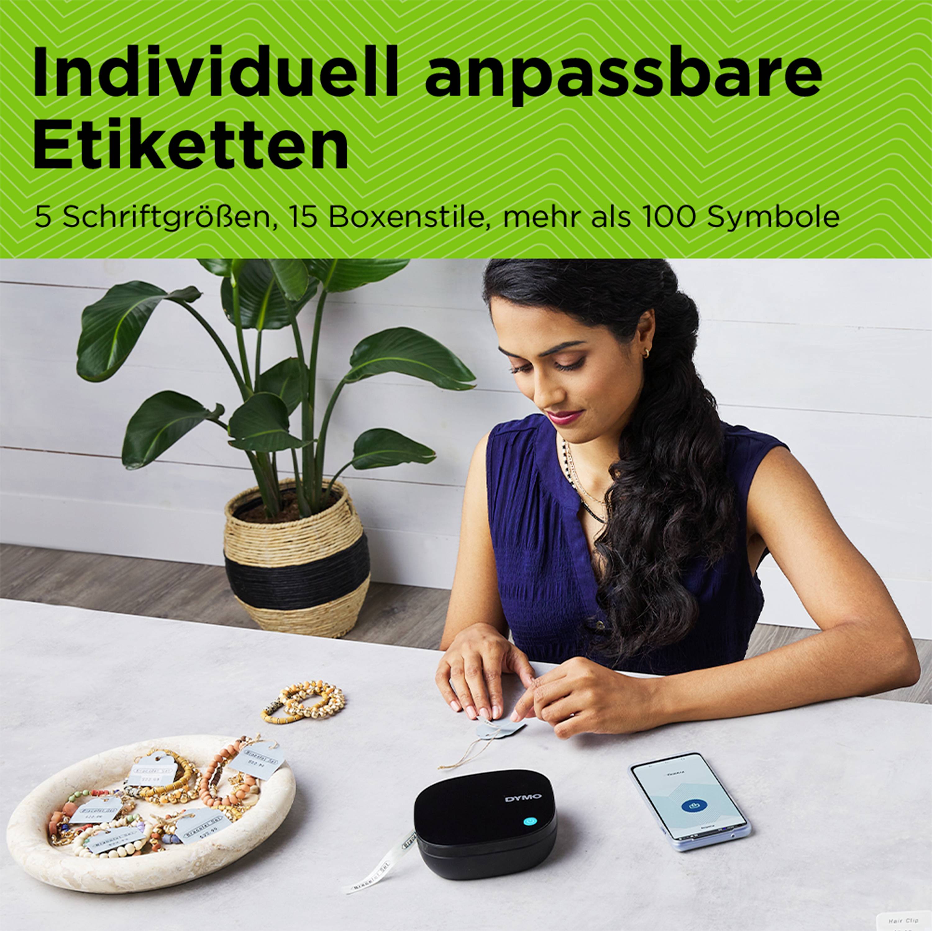 Frau sitzt am Tisch, benutzt vintez Drucker mit Smartphone-App für Etiketten. Text: 'Individuell anpassbare Etiketten'.