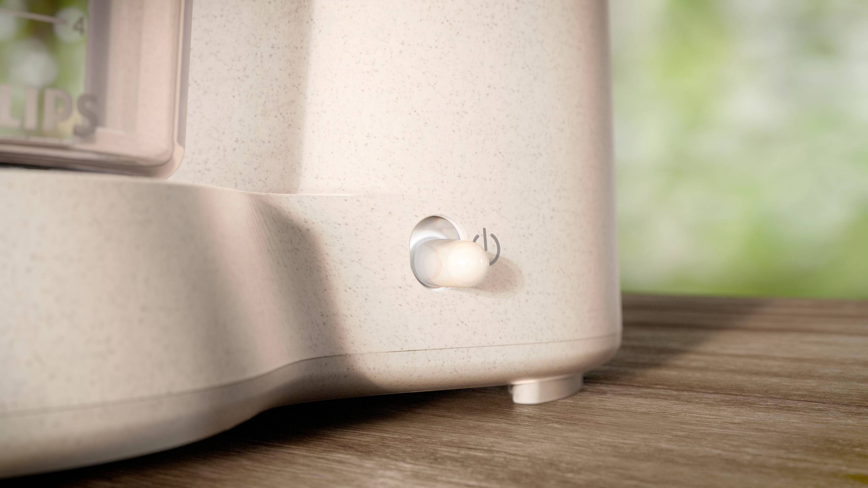 Toaster mit Schalter in Nahaufnahme. Der Fokus liegt auf einem beleuchteten Ein/Aus-Schalter. Der Hintergrund ist unscharf.