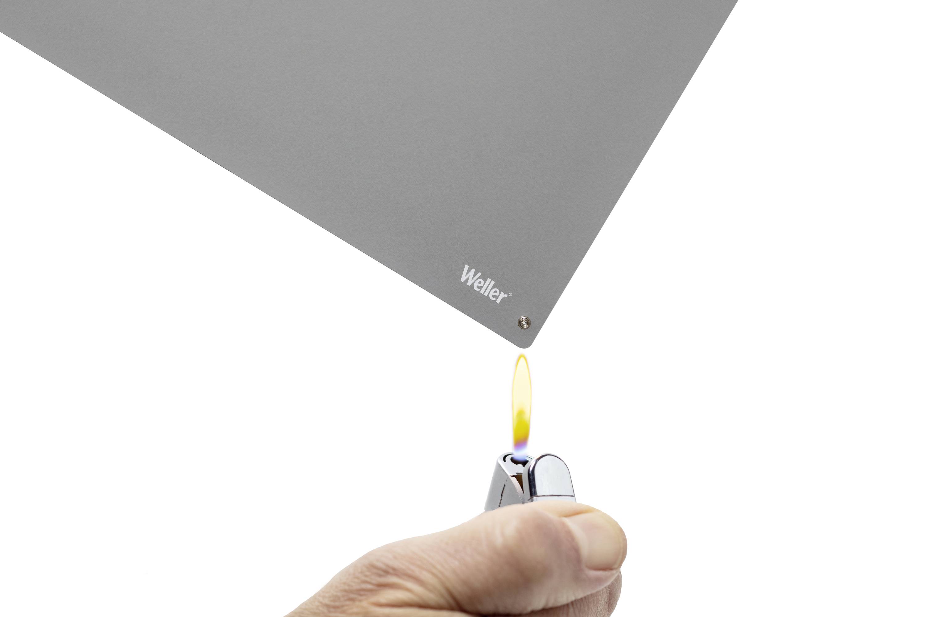 'Weller'-Marke auf einer grauen Oberfläche nahe an einer entzündeten Feuerzeugflamme. Testbild zur Materialbeständigkeit gegenüber Hitze.