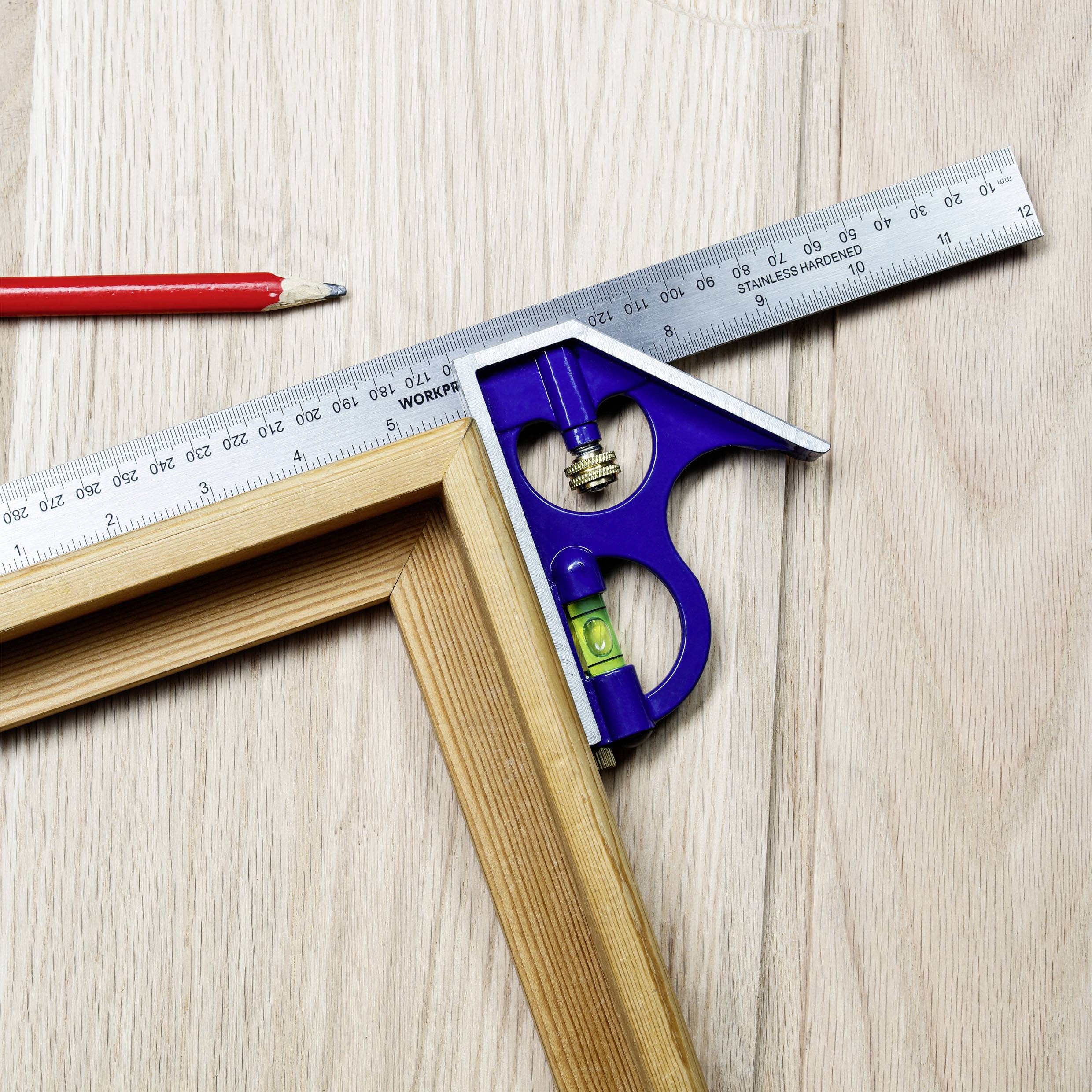 Holzwinkel und blauer Winkelmesser mit Wasserwaage auf hellem Holztisch neben einem roten Bleistift.