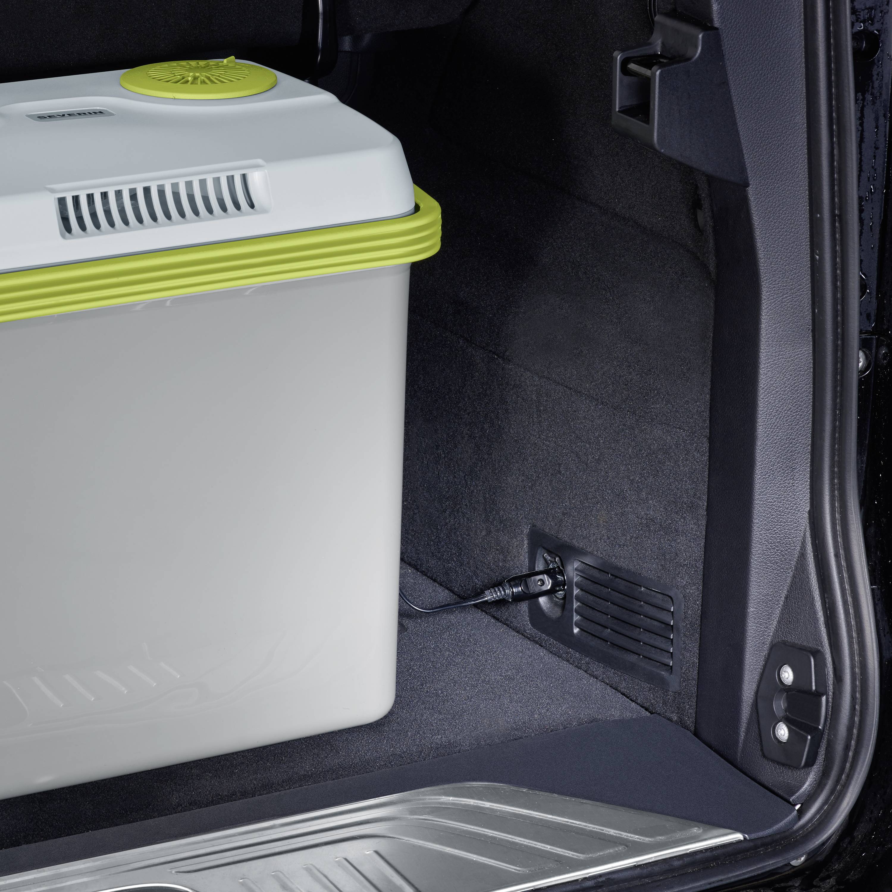 Kühlbox im Kofferraum eines Autos, geöffnet mit sichtbarem Innenbereich. Die Box ist weiß mit grünem Rand.