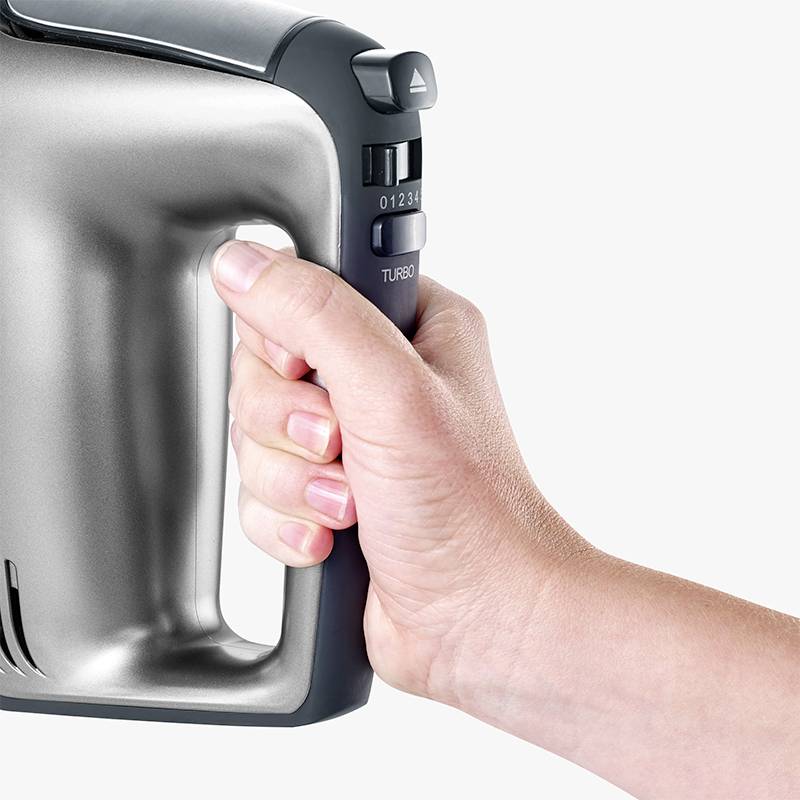 Eine Hand hält einen grauen Handmixer mit sichtbarer 'Turbo'-Taste und Geschwindigkeitsregler am Griff.