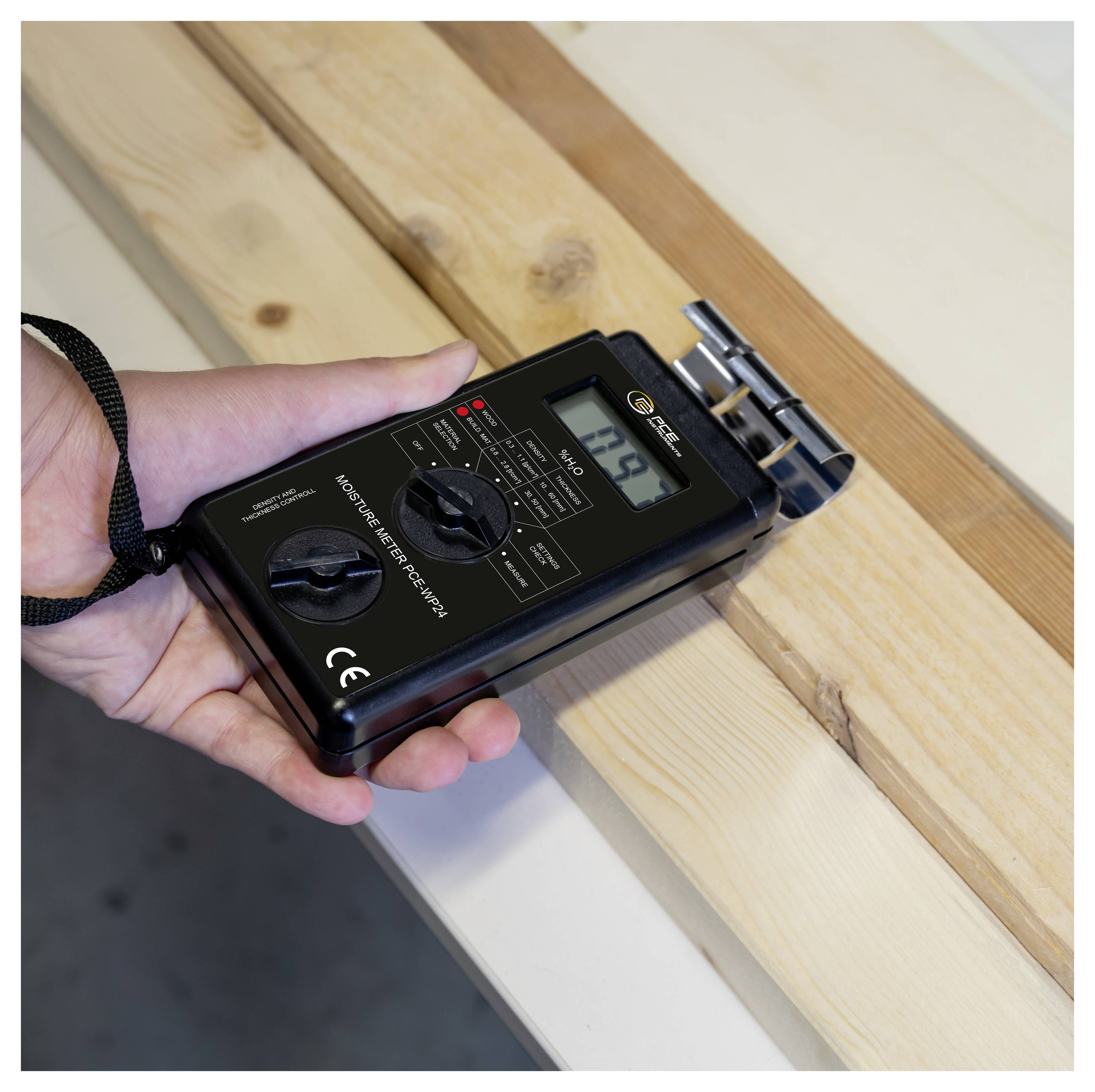 Tragbares digitales Holzfeuchtemessgerät, das ein Holzbrett misst, mit Messspitzen, die in das Brett gedrückt werden, und einem Display, das den Feuchtigkeitsgrad anzeigt.