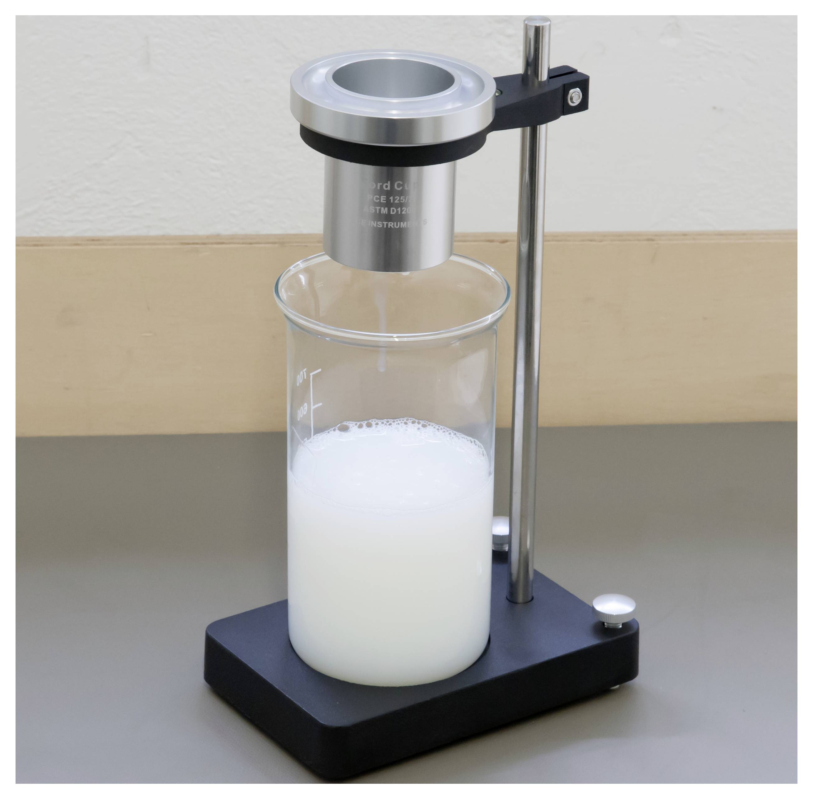 Laborviskosimeter misst eine weiße Flüssigkeit in einem Becher auf einem Ständer.