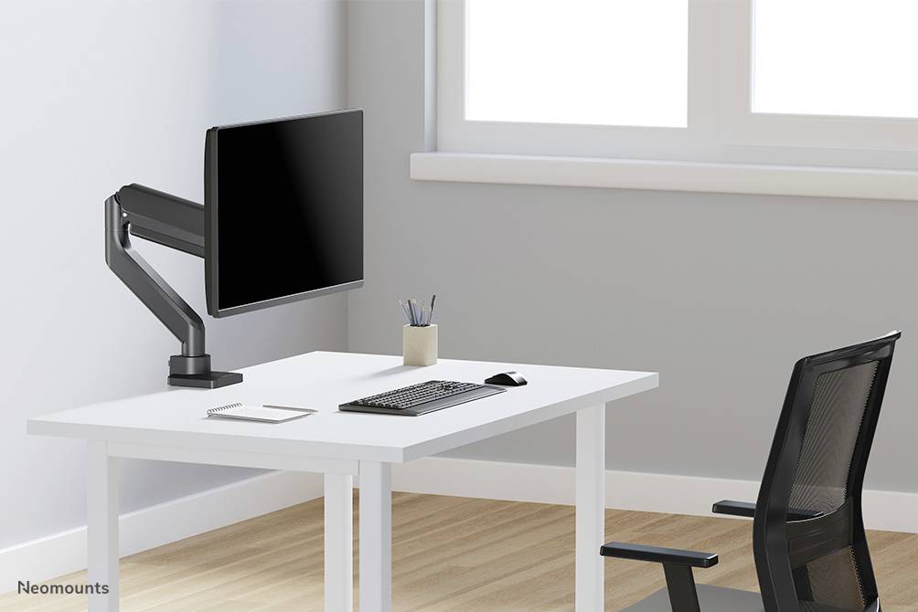 Ein moderner Schreibtisch mit einem schwarzen Monitorarm, Monitor, Tastatur, Maus und Stifteköcher. Ein schwarzer Bürostuhl steht daneben.