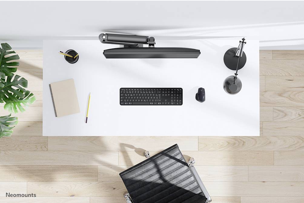 Moderner, aufgeräumter Schreibtisch von oben gesehen mit Tastatur, Maus, Lampe, Notizbuch, Stift und Pflanze. Hochwertiger Bürostuhl.