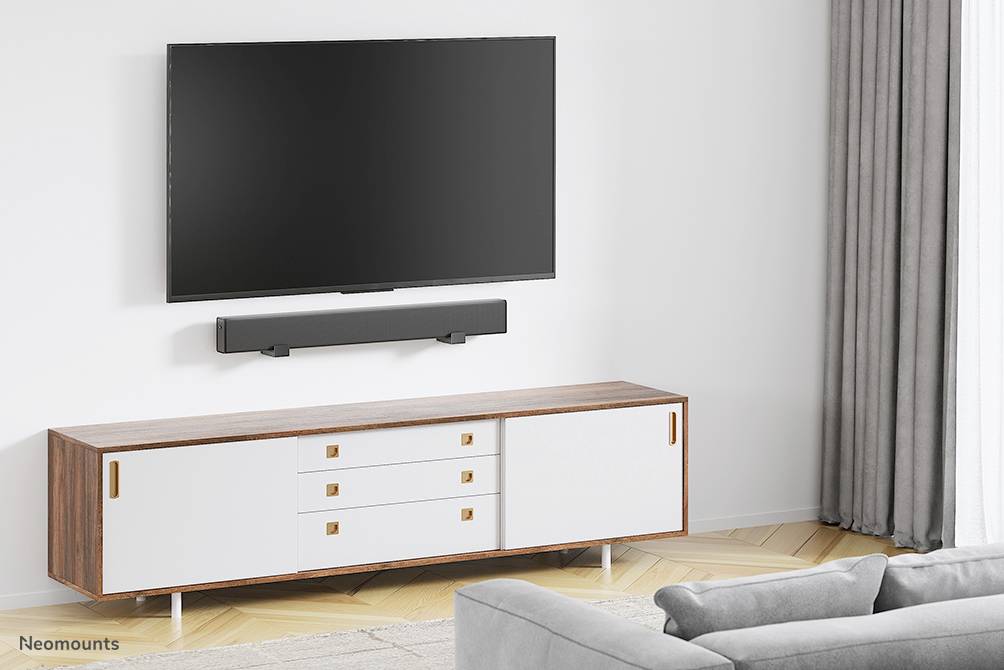 Ein Wohnzimmer mit einem an der Wand montierten Fernseher über einer Soundbar. Darunter steht ein modernes, minimalistisches Lowboard.