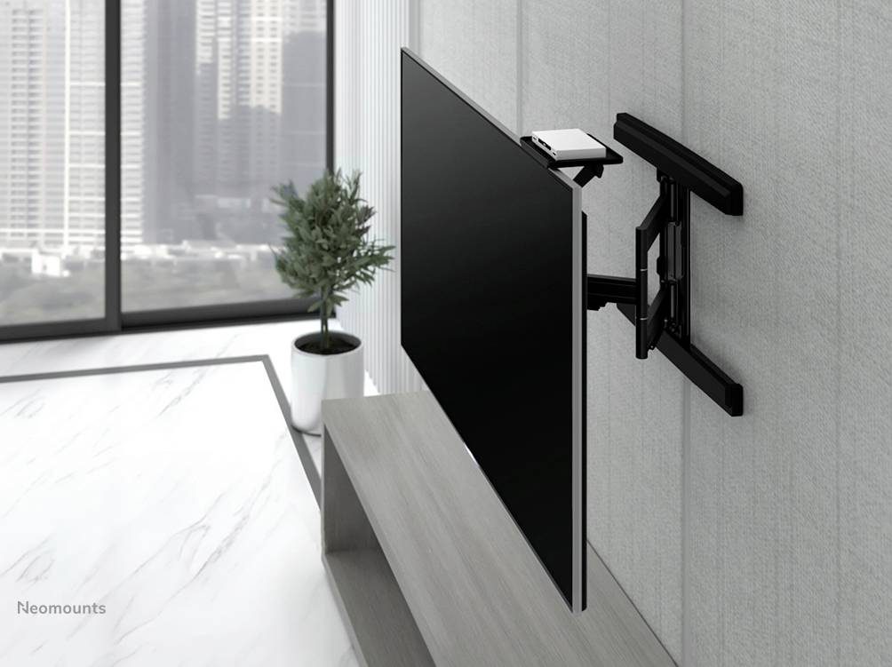 Ein Flachbildfernseher ist an einer schwenkbaren Wandhalterung in einem modernen Wohnzimmer montiert. Im Hintergrund sind Fenster mit Stadtblick zu sehen.