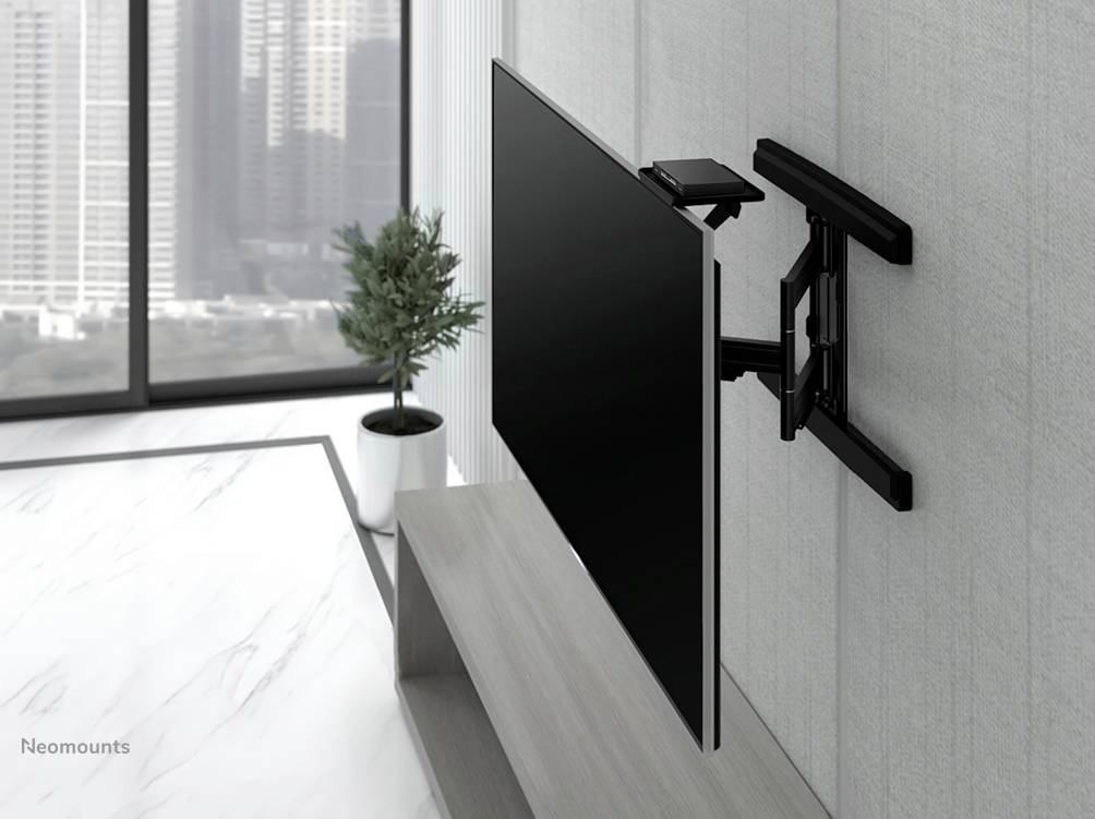 Ein Flachbildfernseher ist an einer schwenkbaren Wandhalterung befestigt. Im Hintergrund sind große Fenster mit Stadtblick zu sehen.