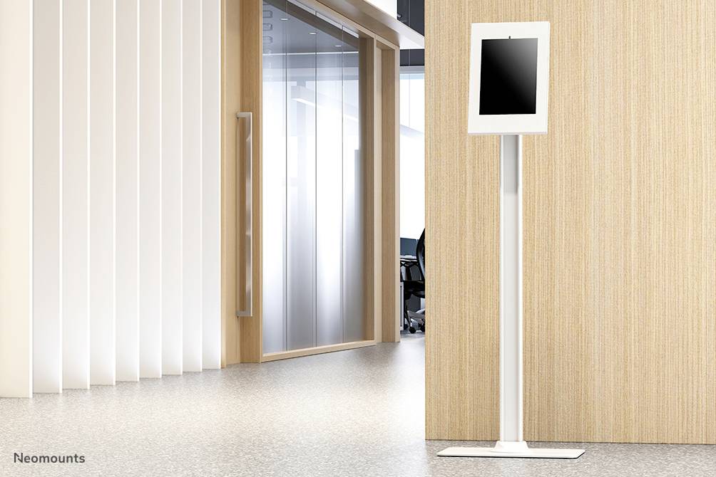 Tablet auf hohem, weißem Ständer vor einer Holz- und Glaswand in modernem Büro.