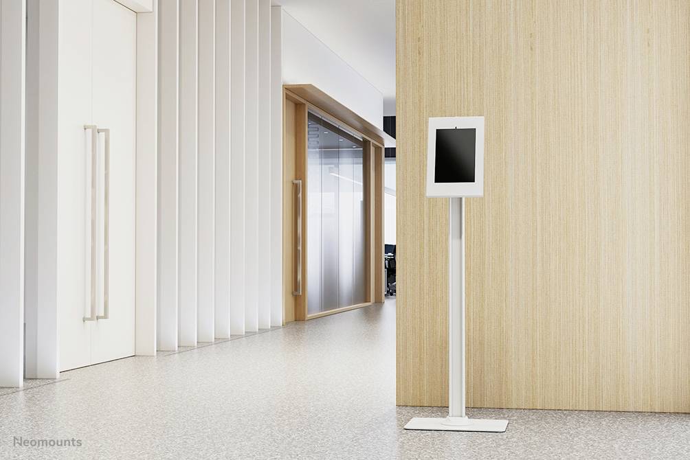 Flur mit hellem Terrazzo-Boden, weißem Wandsockel und hellholzwand. Rechts ein digitaler Kiosk auf weißem Stand.