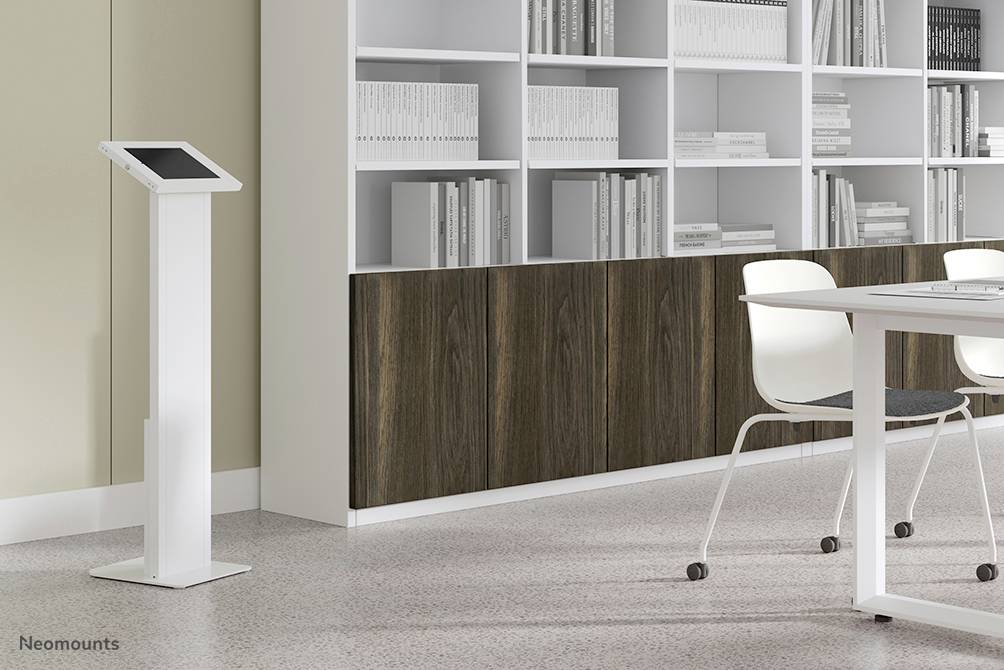 Ein modernes Büro mit einem Tablet auf einem Standfuß, weißen Stühlen, einem Tisch und Bücherregalen im Hintergrund.