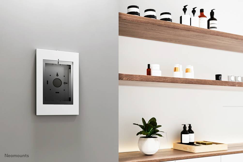 Eine minimalistische Badezimmeranordnung mit Wandspiegel links und Holzregalen rechts, die Pflegeprodukte und eine Pflanze zeigen.