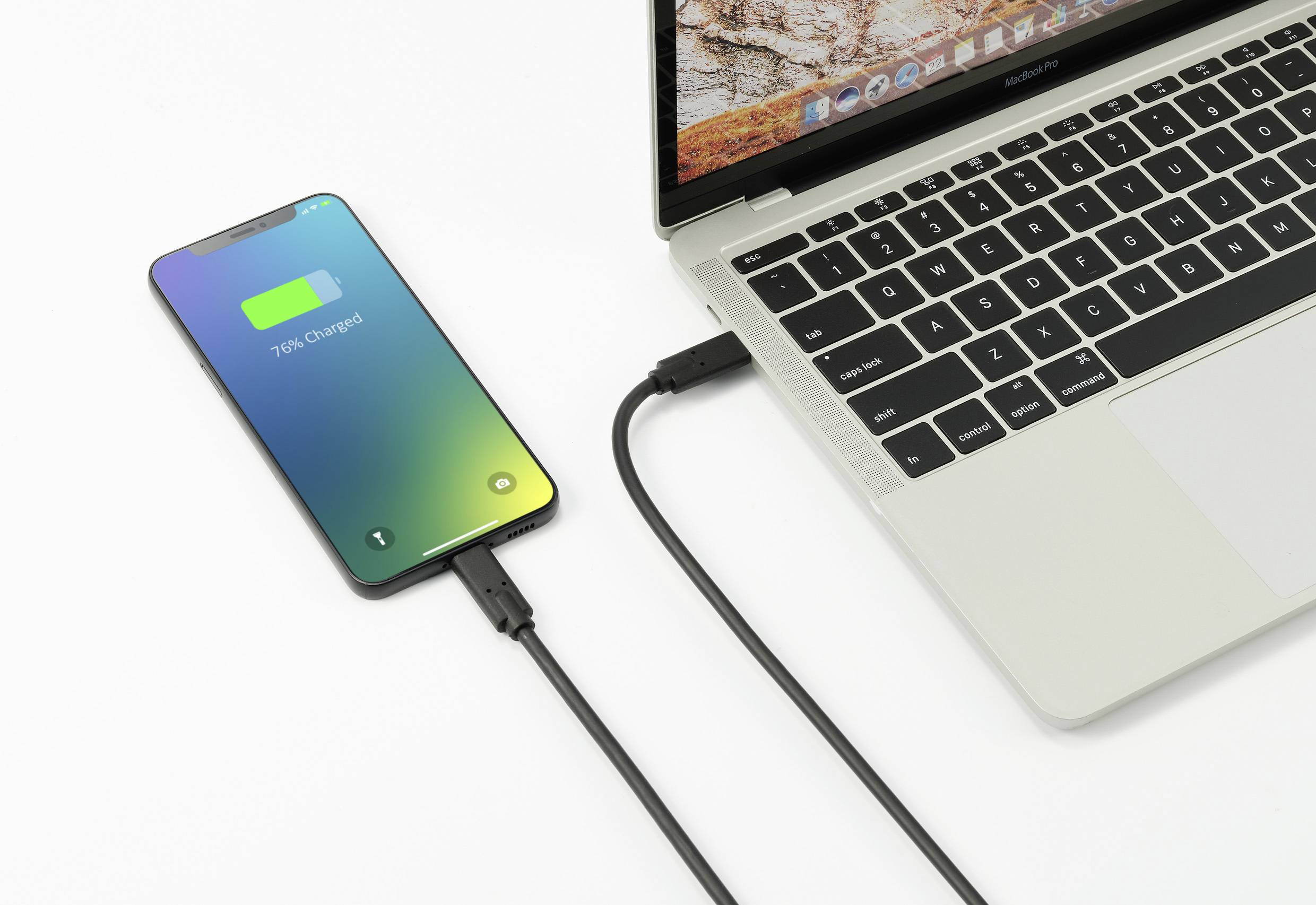 Ein Smartphone wird über ein USB-Kabel an einen Laptop angeschlossen und zeigt '76% geladen'. Der Laptop ist geöffnet und eingeschaltet.