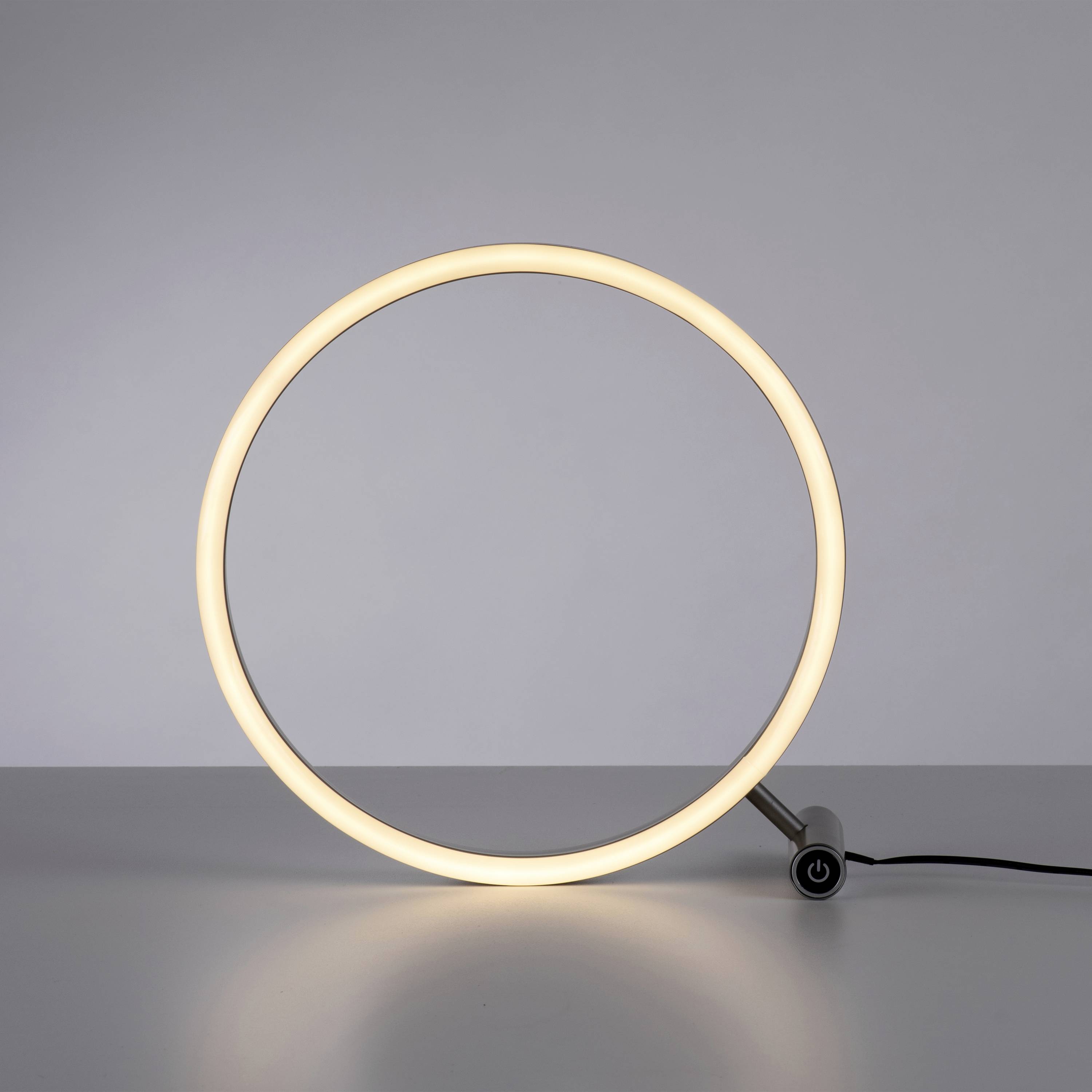 Eine runde, leuchtende Tischlampe aus einem dünnen, kreisförmigen LED-Ring auf einem kleinen Ständer und schwarzem Kabel.