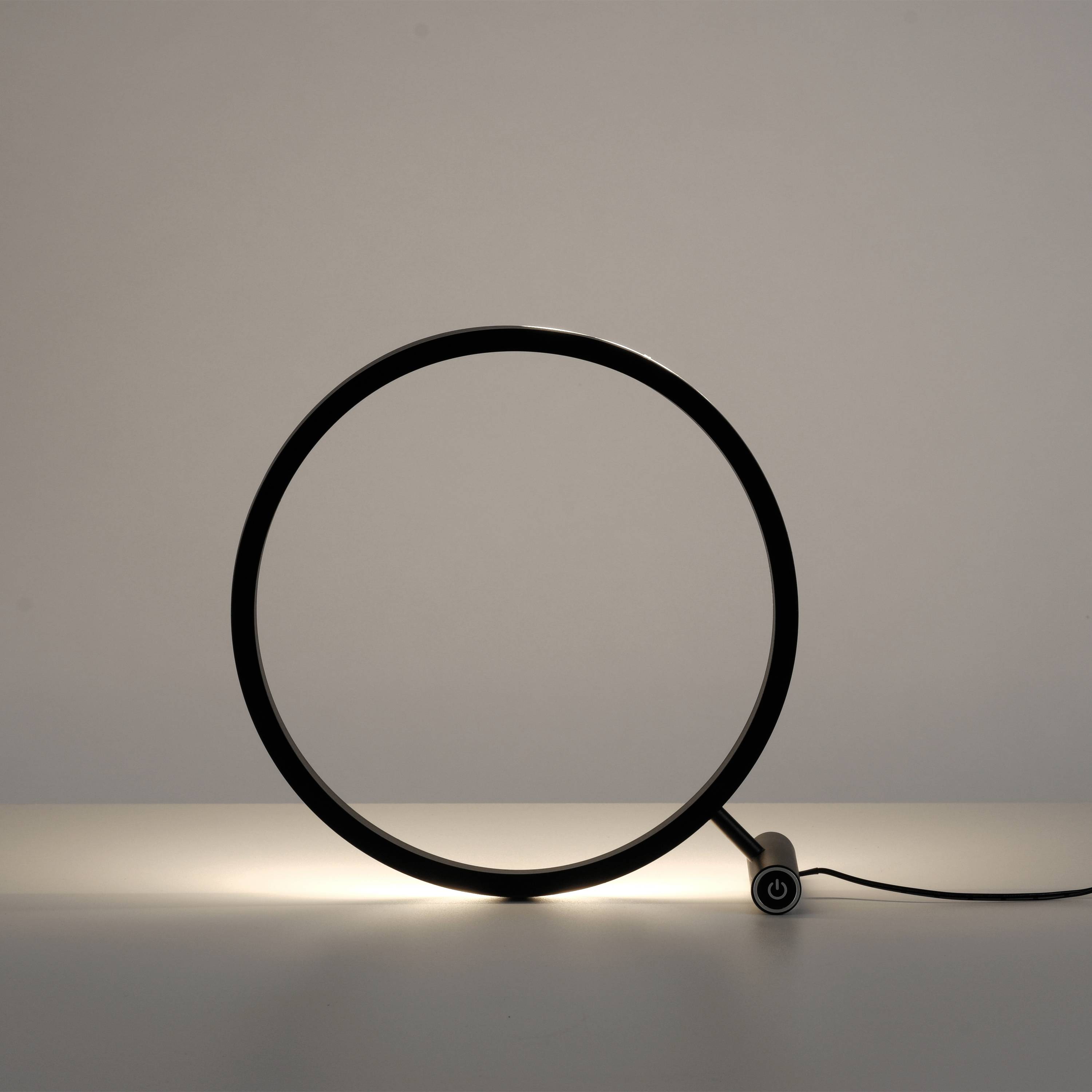 Eine moderne, runde Tischlampe mit einem minimalistischen Design strahlt warmes Licht nach unten auf die Oberfläche aus.