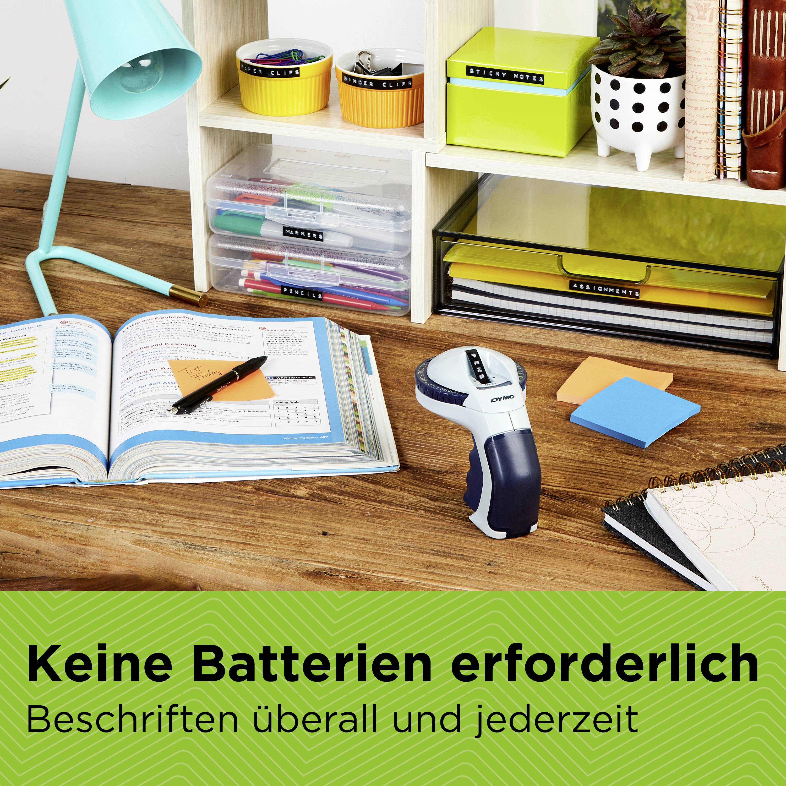 Ein Plastikgerät liegt neben Büchern und Schreibmaterialien auf einem Schreibtisch. Text: 'Keine Batterien erforderlich. Beschriften überall und jederzeit'.