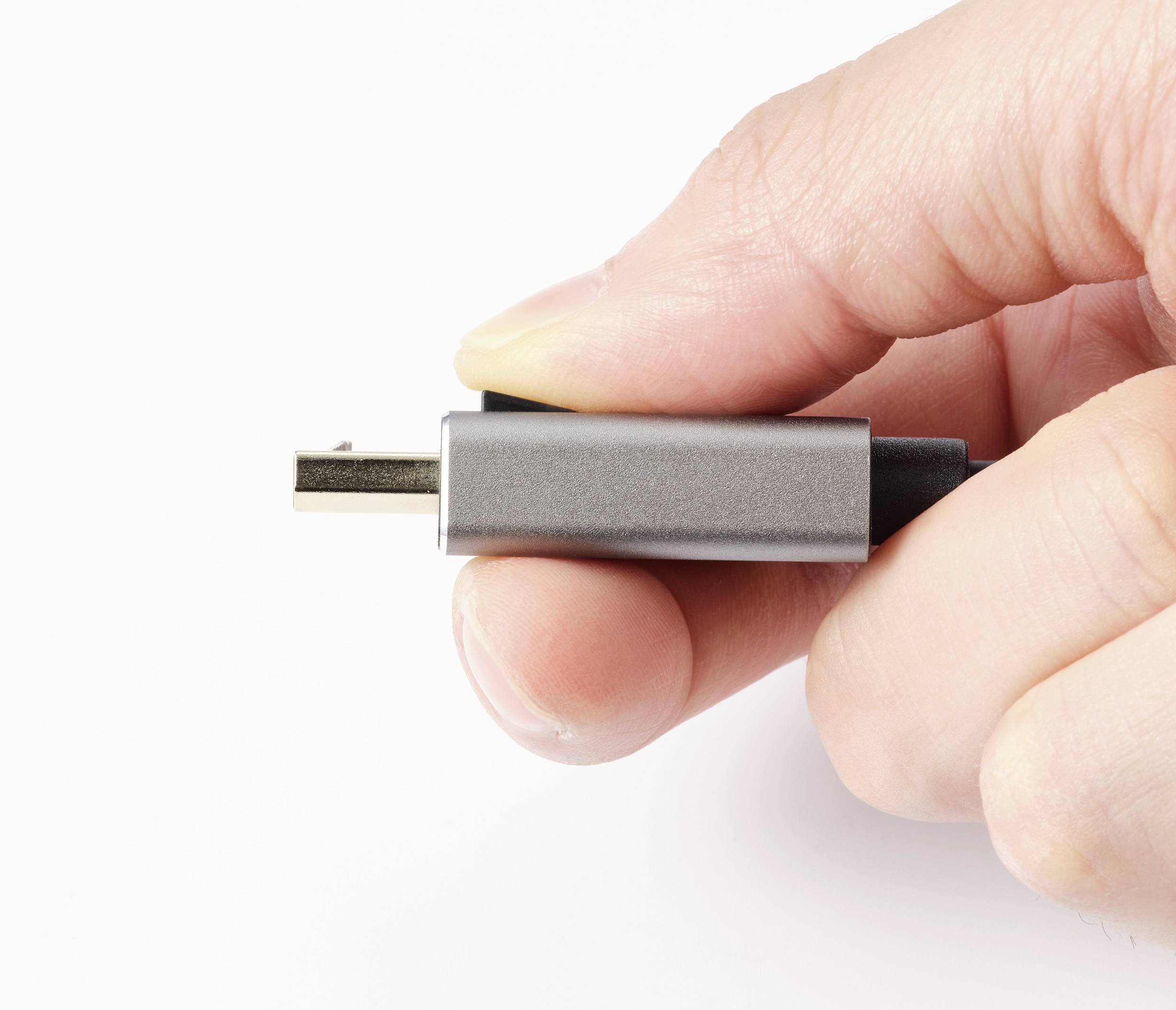 Hand hält einen USB-C-Stecker vor weißem Hintergrund.