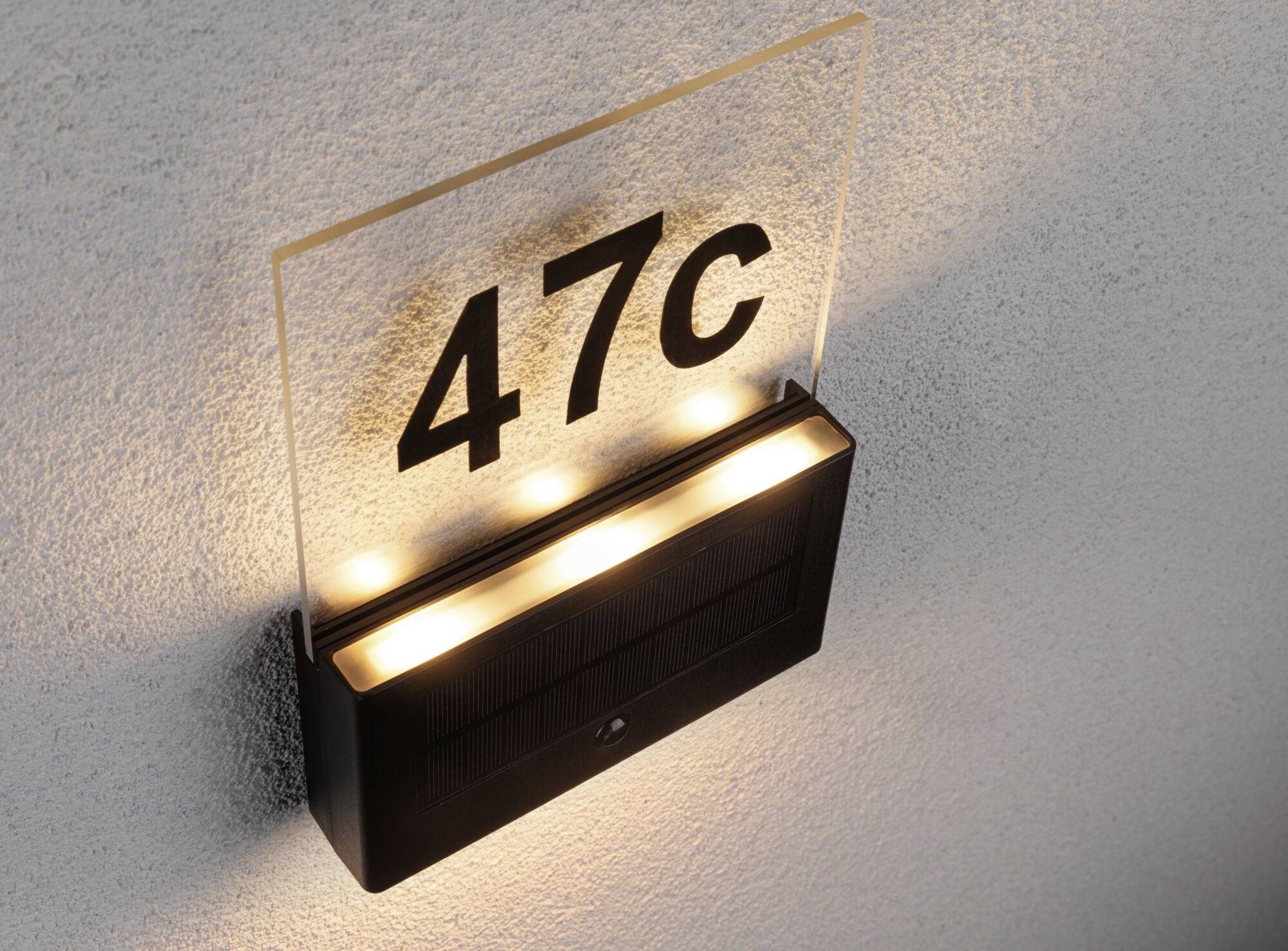 Solarbetriebene Hausnummernbeleuchtung zeigt '47C', montiert an einer Wand.