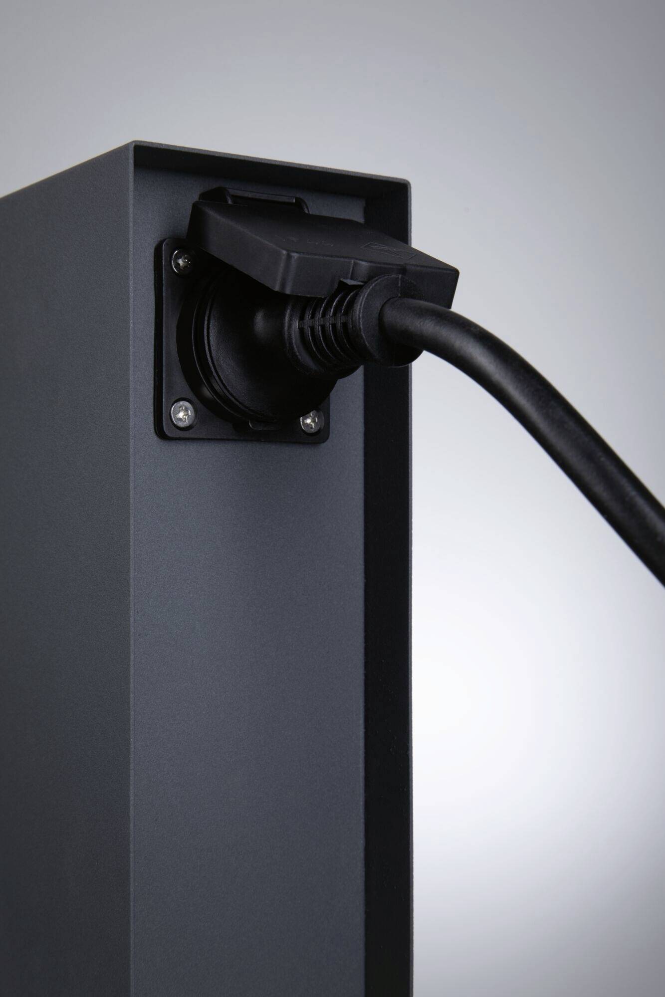 Eine schwarze Ladestation mit angeschlossenem Ladekabel, vermutlich für ein Elektrofahrzeug, vor einem neutralen Hintergrund.