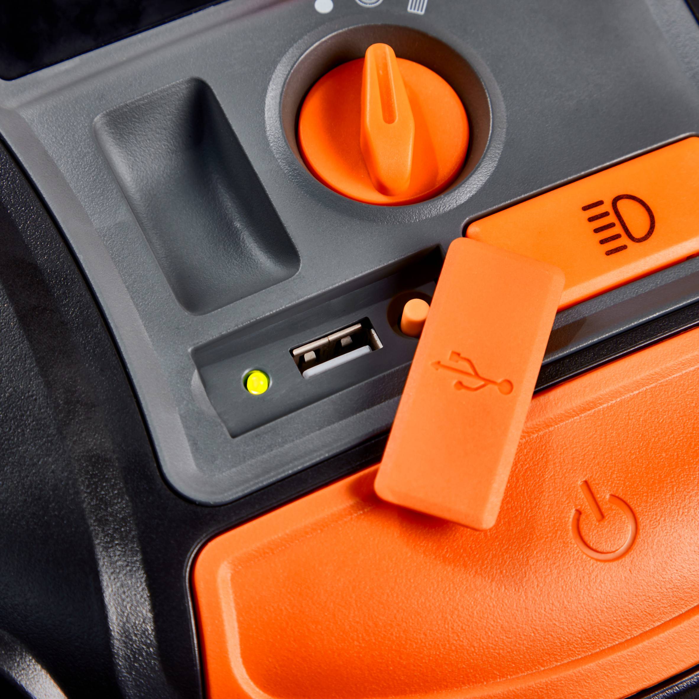 Nahaufnahme einer orangefarbenen Schalterleiste mit einem Schieberegler, einem USB-Anschluss und einem Hauptschalter auf einem Gerät.