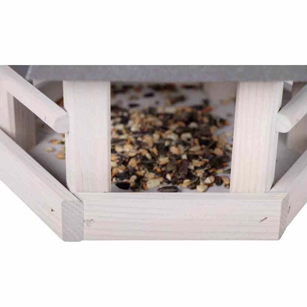 Nahaufnahme eines hölzernen Vogelhauses, das mit einer Mischung aus Samen und Getreide gefüllt ist.