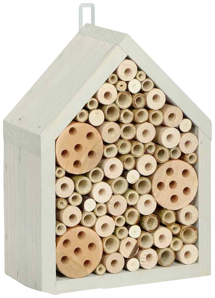 Ein Insektenhotel aus Holz in Form eines Hauses mit Röhren und runden Holzscheiben, dient als Unterschlupf für Insekten.