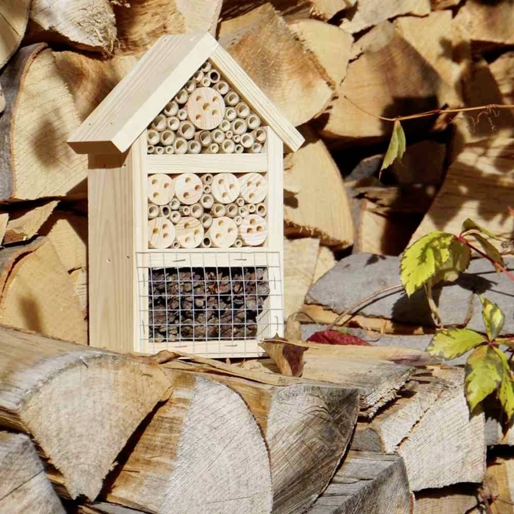 Ein Insektenhotel auf einem Stapel aus Brennholz. Verschiedene natürliche Materialien bieten Nistplätze für Insekten.