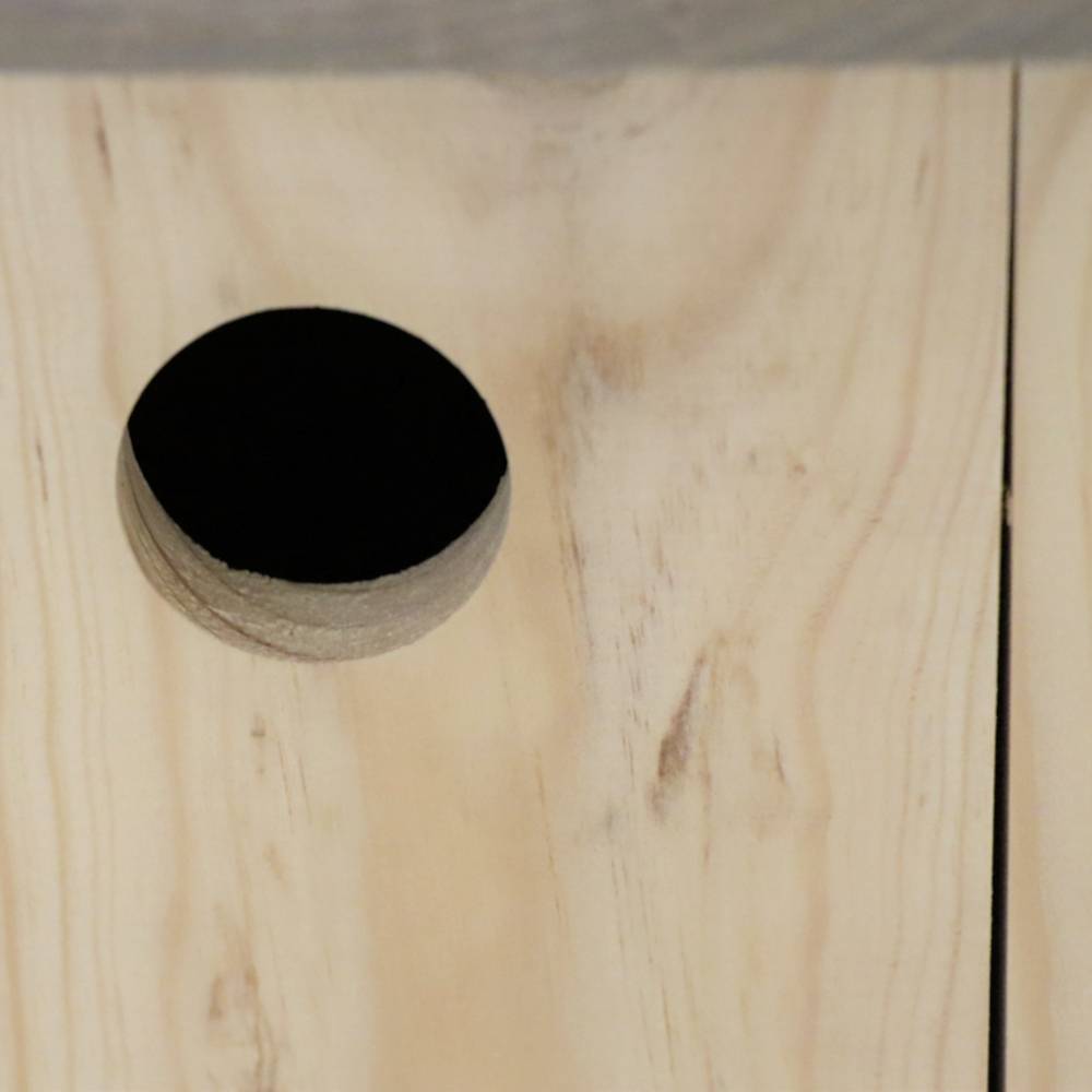 Ein rundes Loch in einer hölzernen Oberfläche, das Teil eines Möbelstücks oder einer Struktur sein könnte.