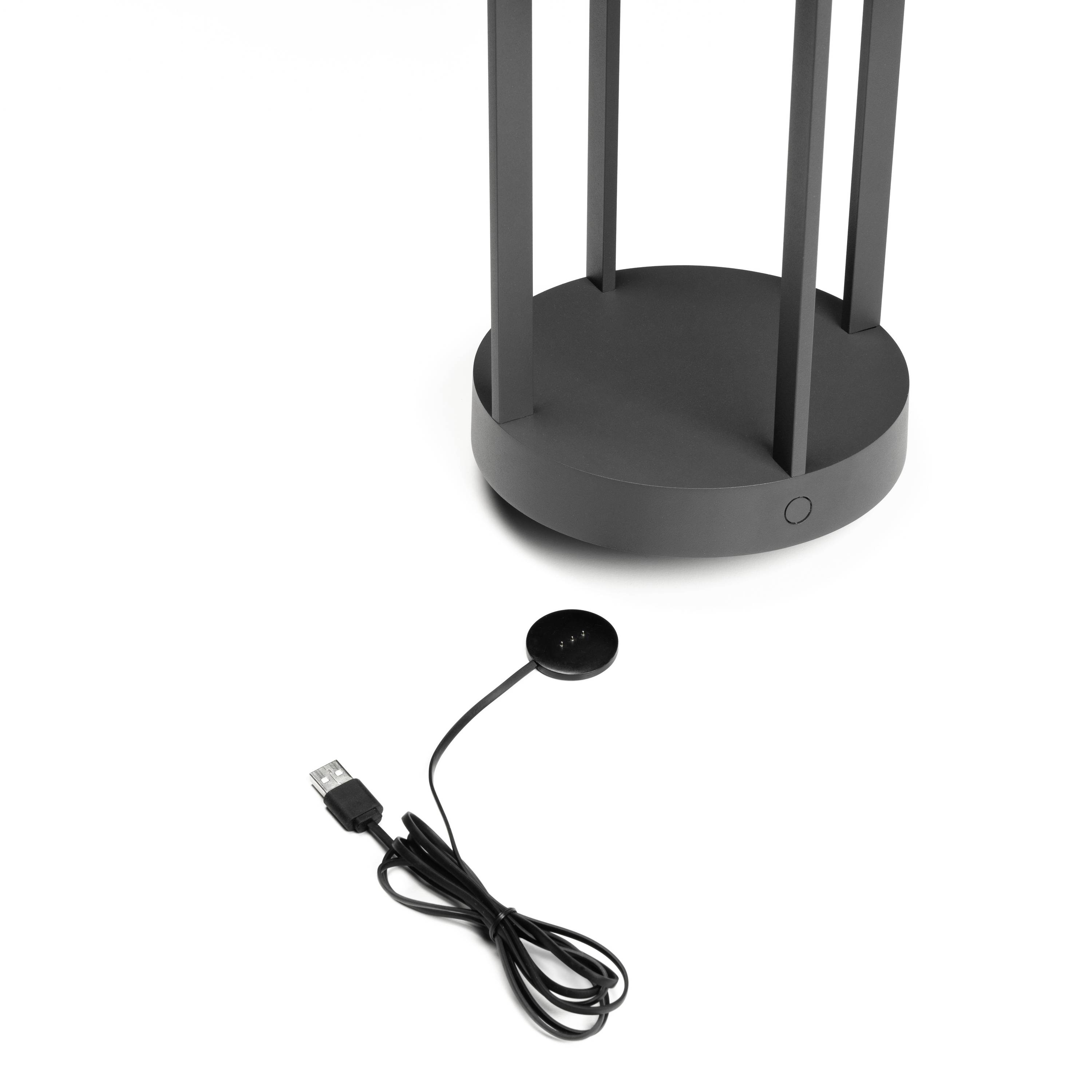 Ein drahtloses Ladegerät mit einem zylinderförmigen Ständer, daneben liegt ein USB-Kabel.