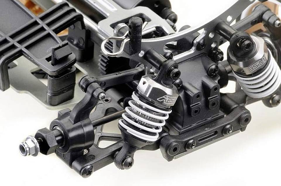 Nahaufnahme eines ferngesteuerten Fahrzeugchassis mit Stoßdämpfern, Federung und Metallteilen, die technische Details zeigen.