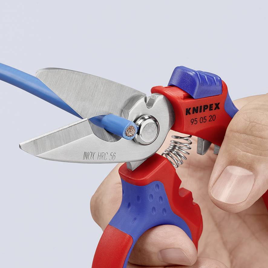 Eine Hand hält einen Drahtschneider, der ein blaues Kabel abschneidet. Der Schneider ist mit 'Knipex INOX HC 56' beschriftet.