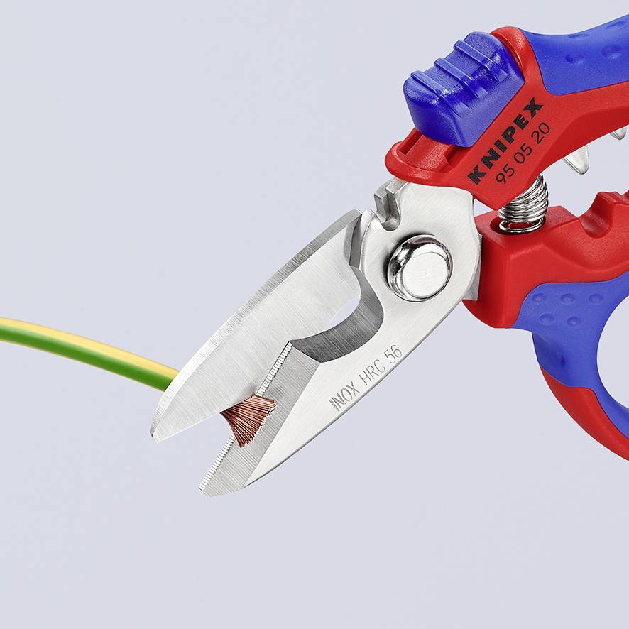 Eine rote und blaue Kabelschere schneidet ein dreifarbiges Kabel ab. Die Klingen sind geöffnet, und das Kupfer des Kabels ist sichtbar.