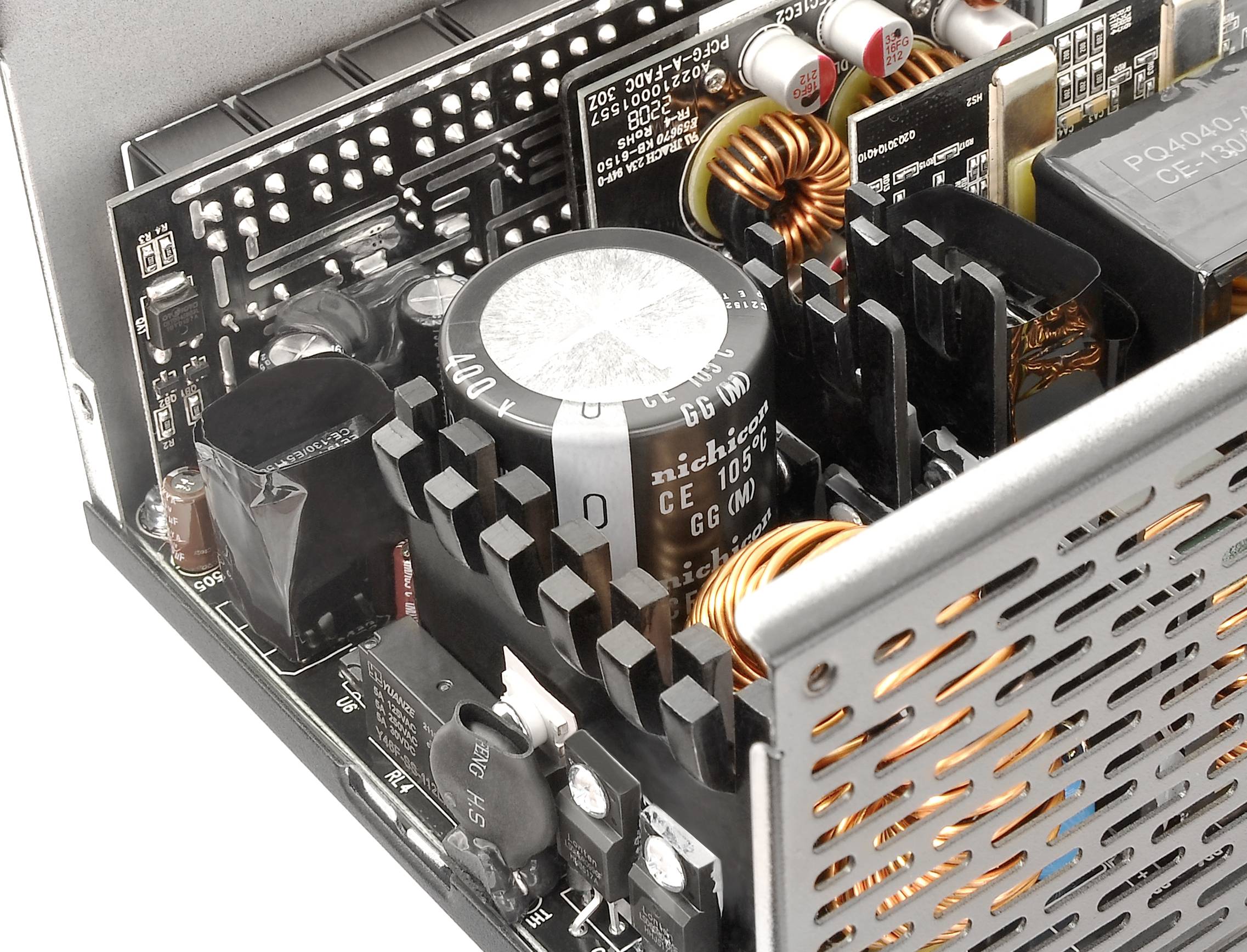 Nahaufnahme einer Computer-Netzteilplatine mit verschiedenen elektronischen Komponenten wie Kondensatoren, Spulen und Kühlkörpern.