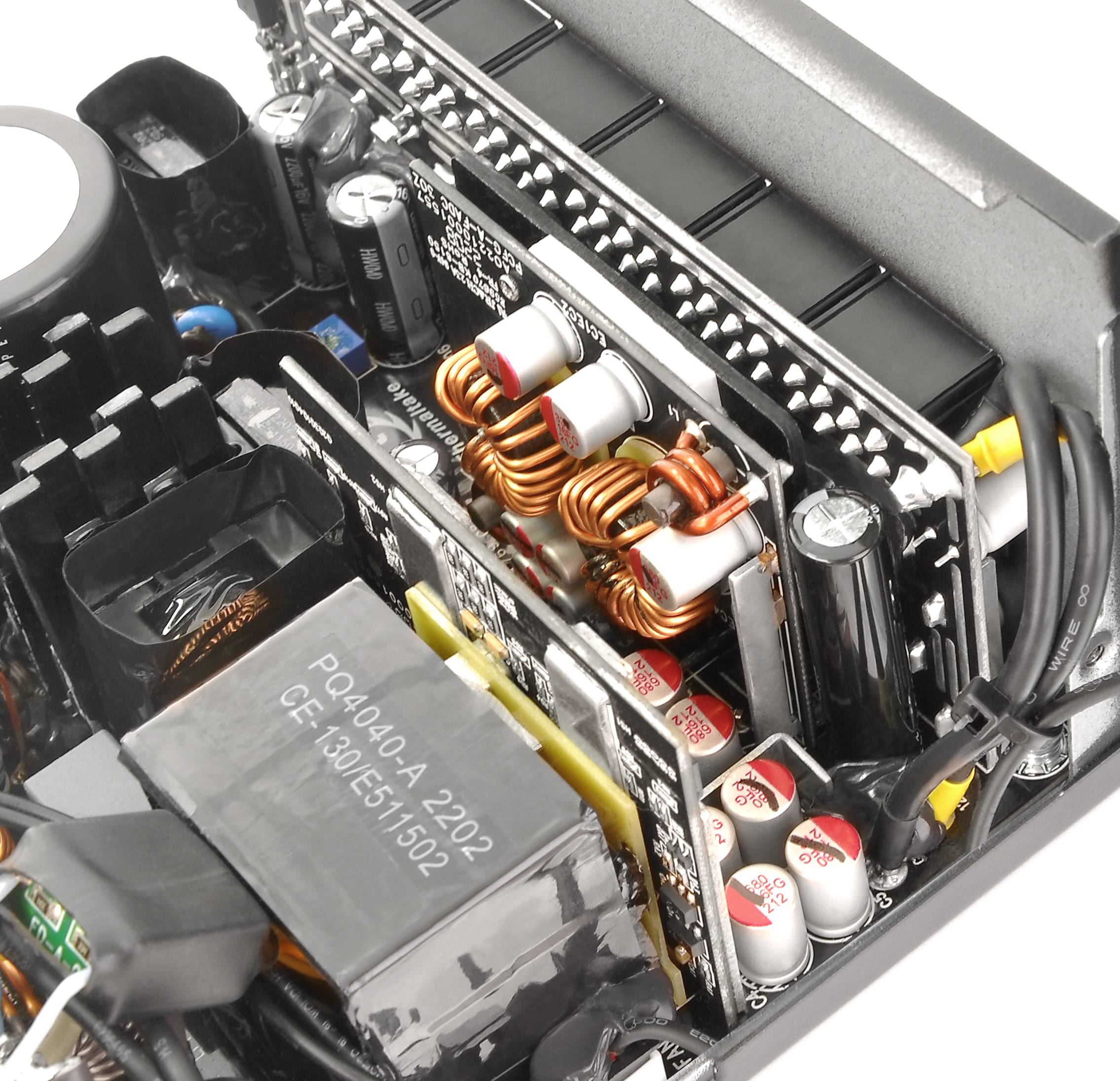 Ein geöffneter Computer-Netzteil zeigt Kondensatoren, Spulen und Kühlungskomponenten. Elektronische Bauteile sind dicht angeordnet.