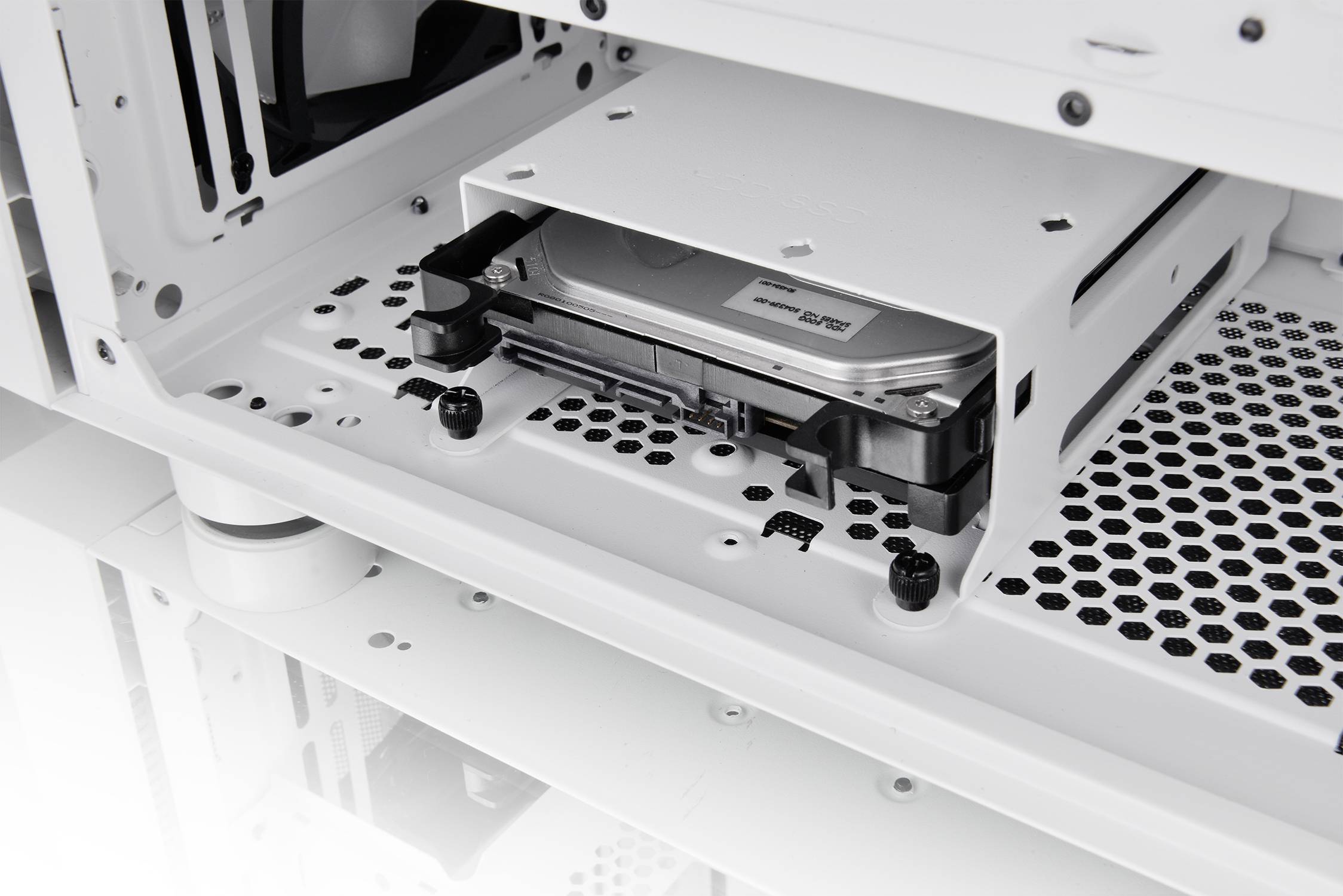 Ein Computergehäuse zeigt eine eingebaute Festplatte in einem Schacht, umgeben von Lüftungsschlitzen und Kabeldurchführungen.