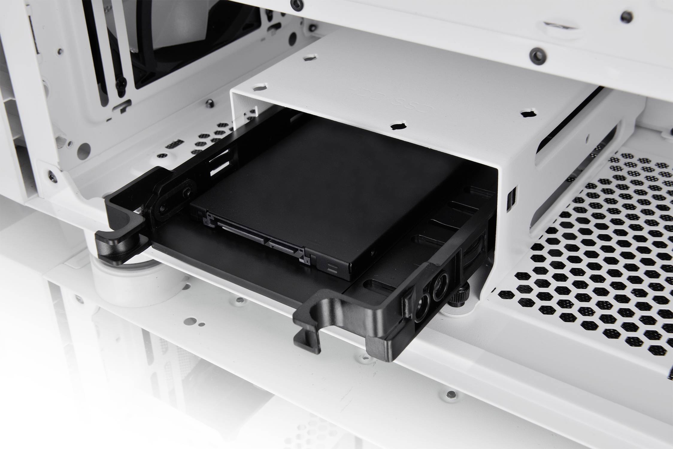 Schwarze Festplatte wird in ein weißes Computergehäuse eingesetzt. Der Blick zeigt den Einschubmechanismus und Innenraum des Gehäuses.
