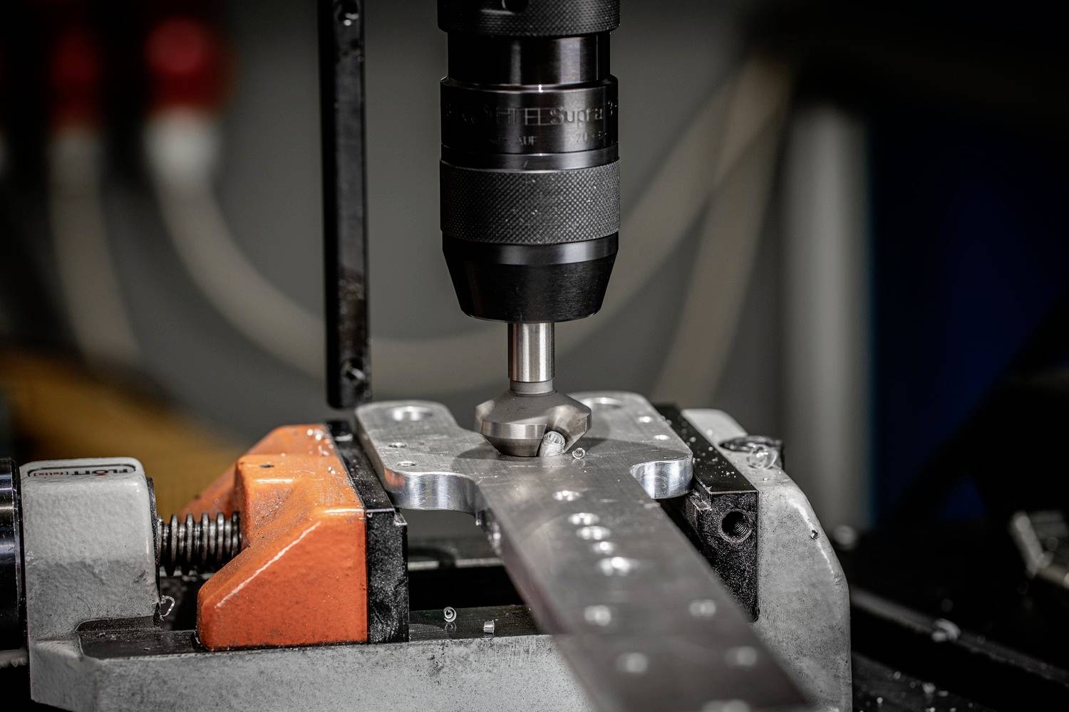 Eine Maschine bearbeitet ein Metallstück in einer Werkstatt, umgeben von präzisen Werkzeugen.