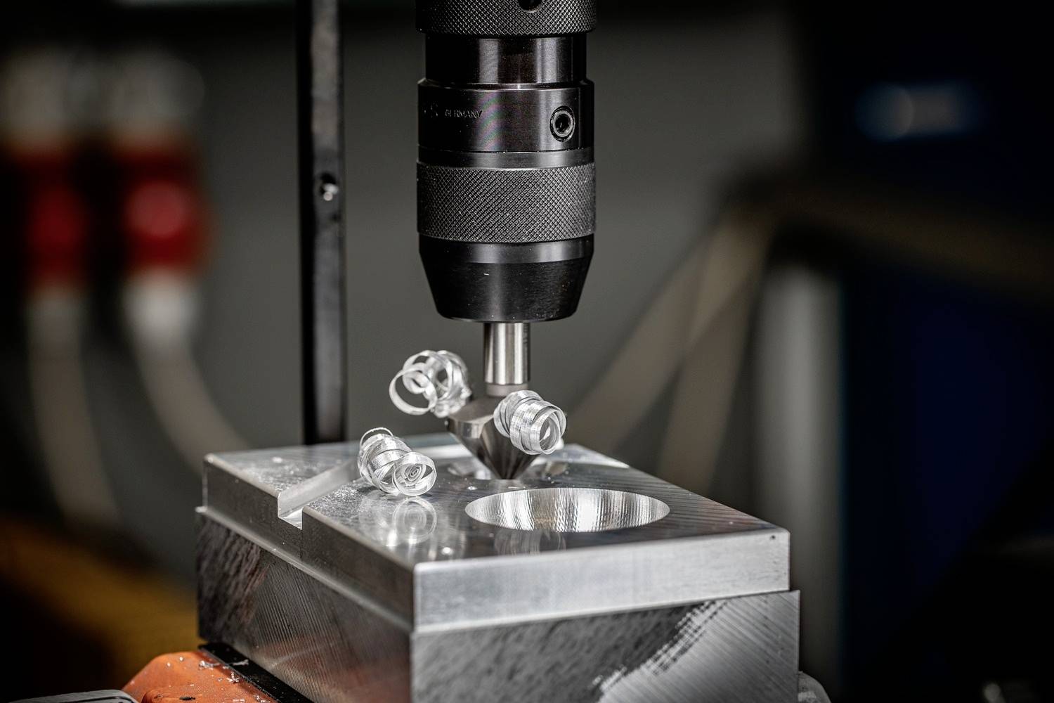Nahaufnahme einer CNC-Maschine, die präzise Metallbohrarbeiten an einem Werkstück ausführt. Vier Bolzen sind sichtbar fixiert.