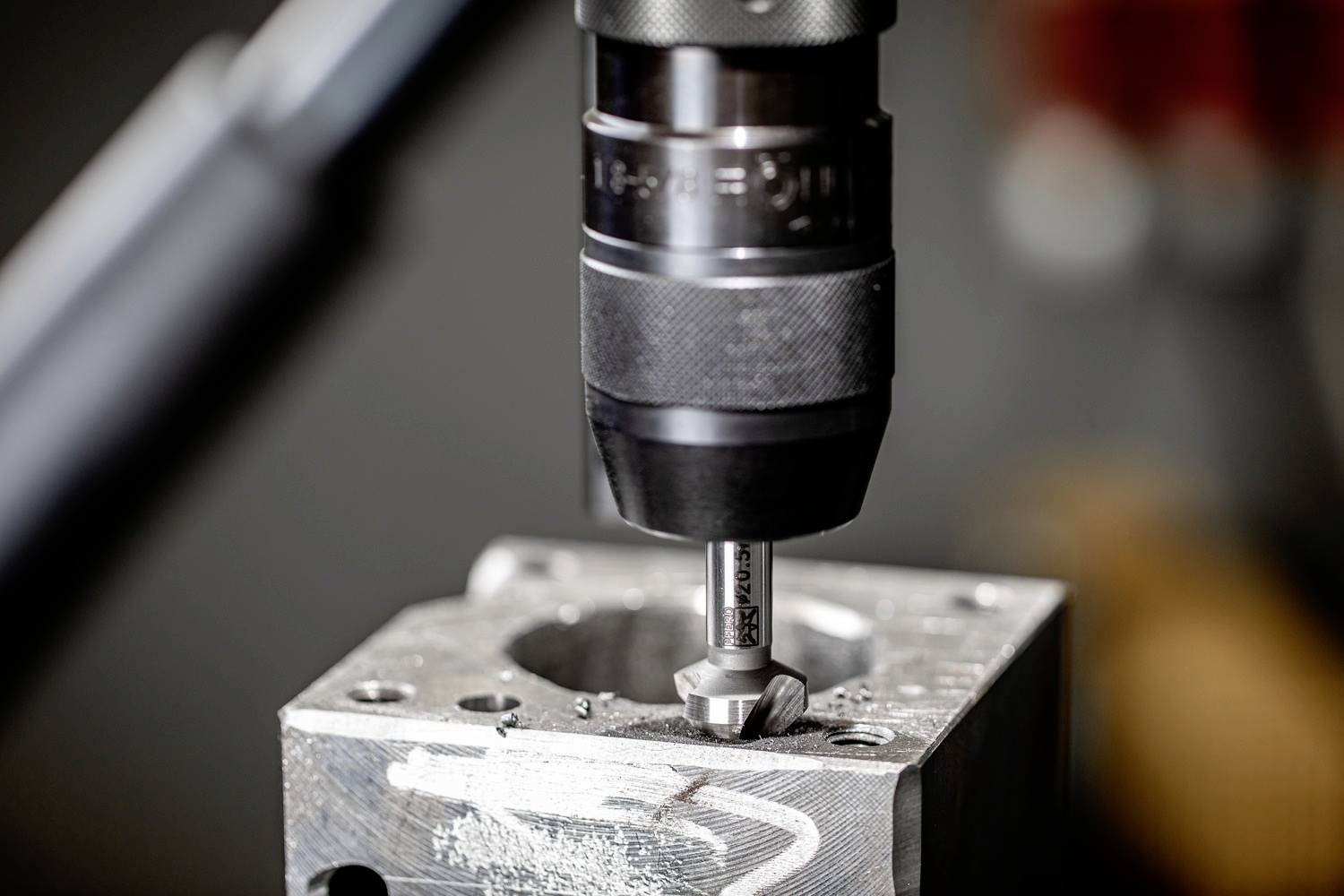 Nahaufnahme einer Bohrmaschine, die ein Metallstück bearbeitet. Die Maschine bohrt präzise an der markierten Stelle des Materials.