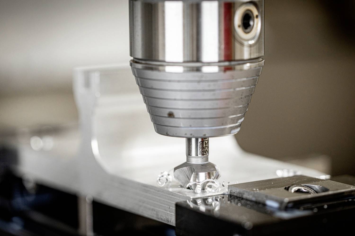 Nahaufnahme einer CNC-Fräsmaschine, die Metall bearbeitet. Die Maschine entfernt präzise Material von einem Metallstück.