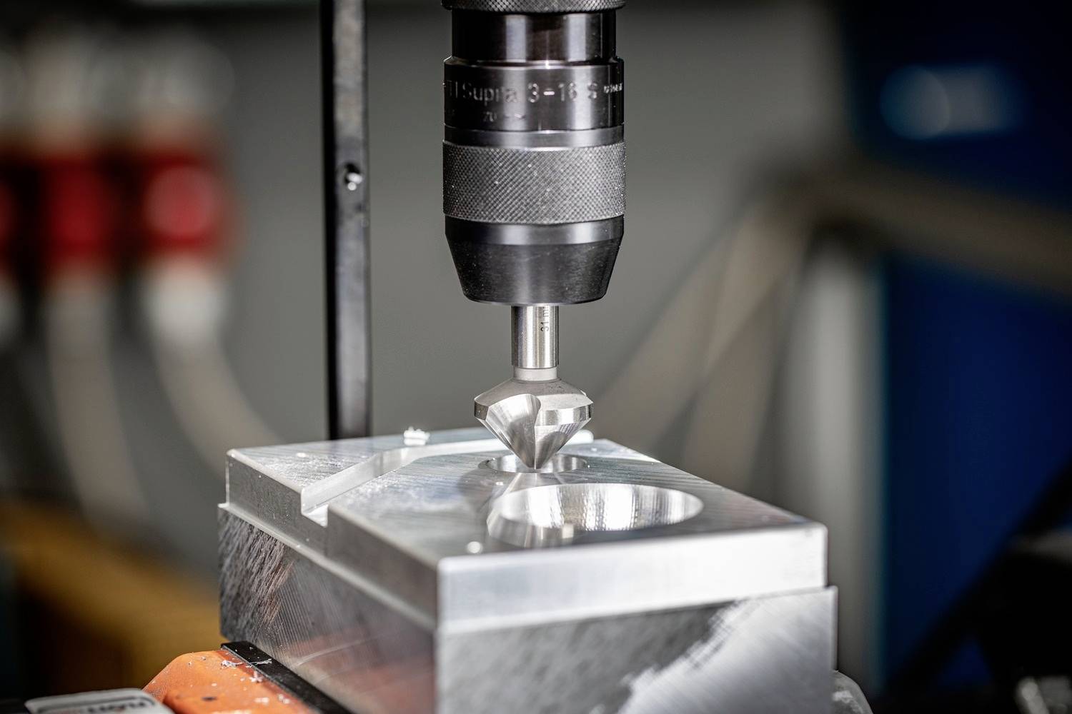 Eine CNC-Maschine fräst präzise ein Metallteil in einer Werkstatt. Die Fräse ist auf das Metallstück zentriert und führt einen Bohrvorgang durch.