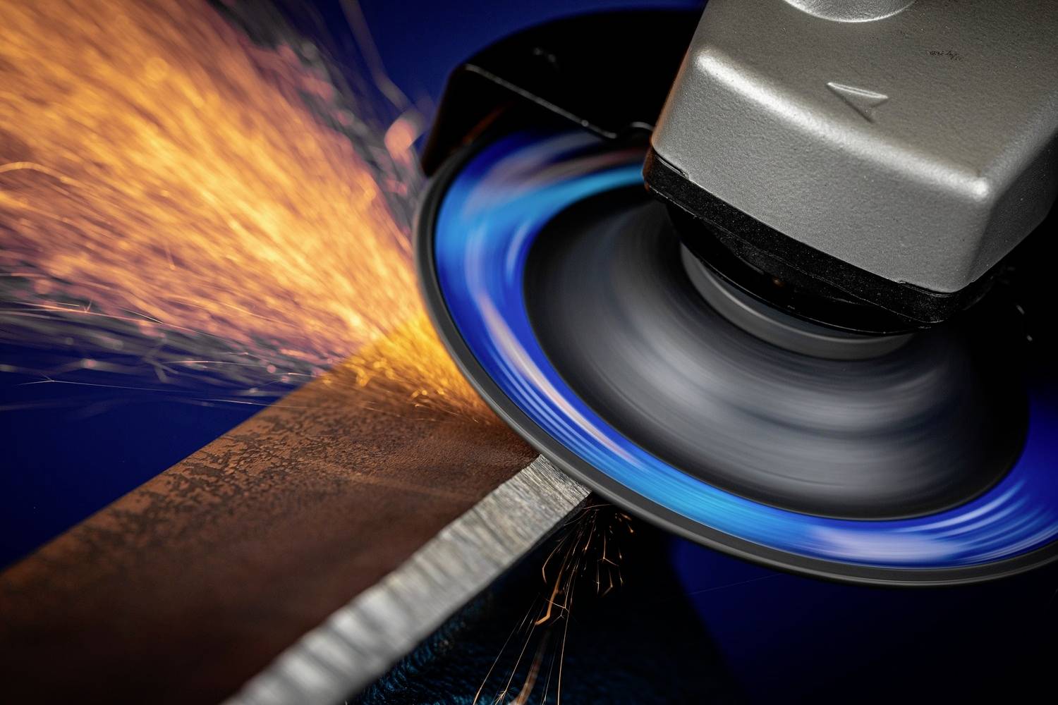 Ein Winkelschleifer schleift Metall, sprüht Funken. Hauptfokus auf Schleifscheibe und Funken. Actionreiches Handwerksbild.