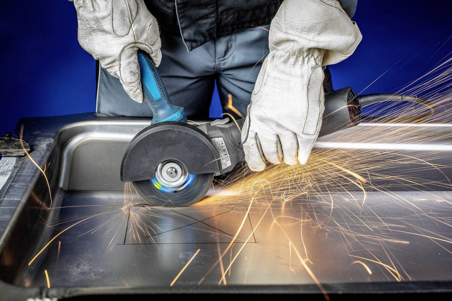 Person mit Schutzhandschuhen schneidet Metall mit einer Winkelschleifmaschine, Funken fliegen zur Seite.
