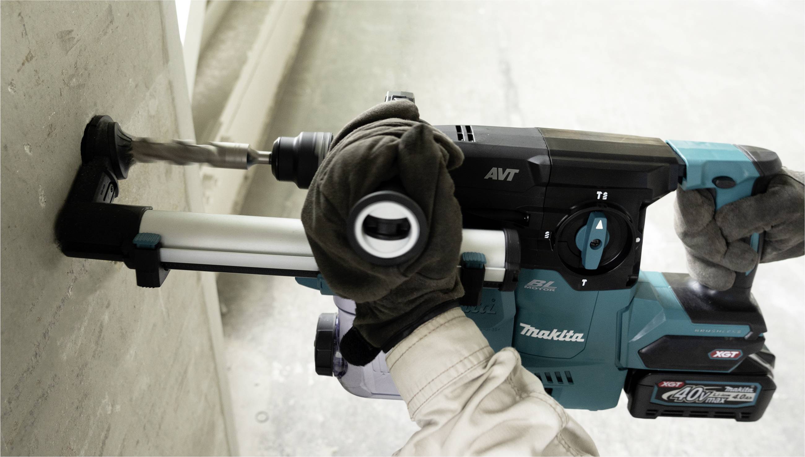 Eine Person benutzt eine elektrische Bohrmaschine, um ein Loch in eine Betonwand zu bohren. Die Bohrmaschine ist blau und von der Marke Makita.