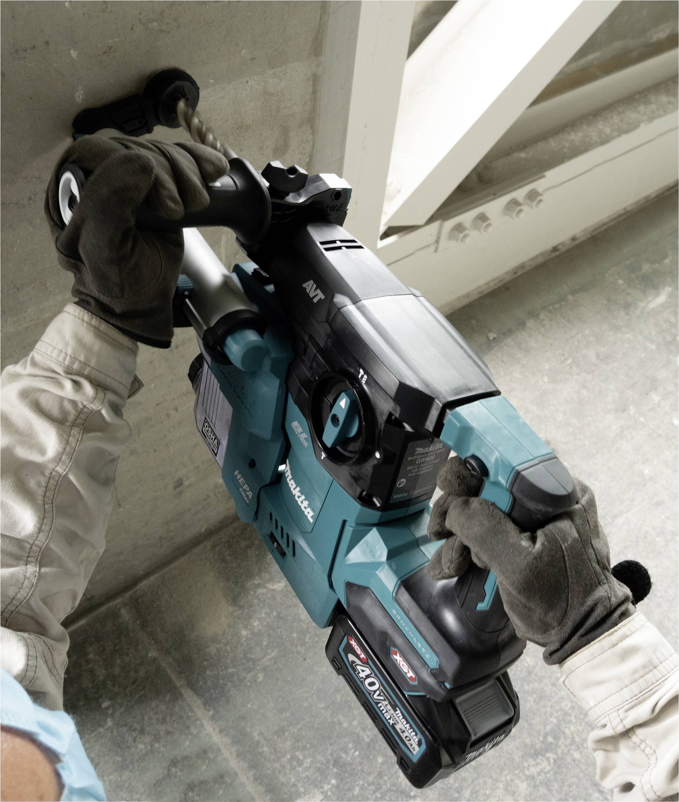 Eine Person mit Handschuhen bedient ein blau-schwarzes Elektrowerkzeug an einer Betonwand. Das Werkzeug hat eine 40V-Akkuanzeige.