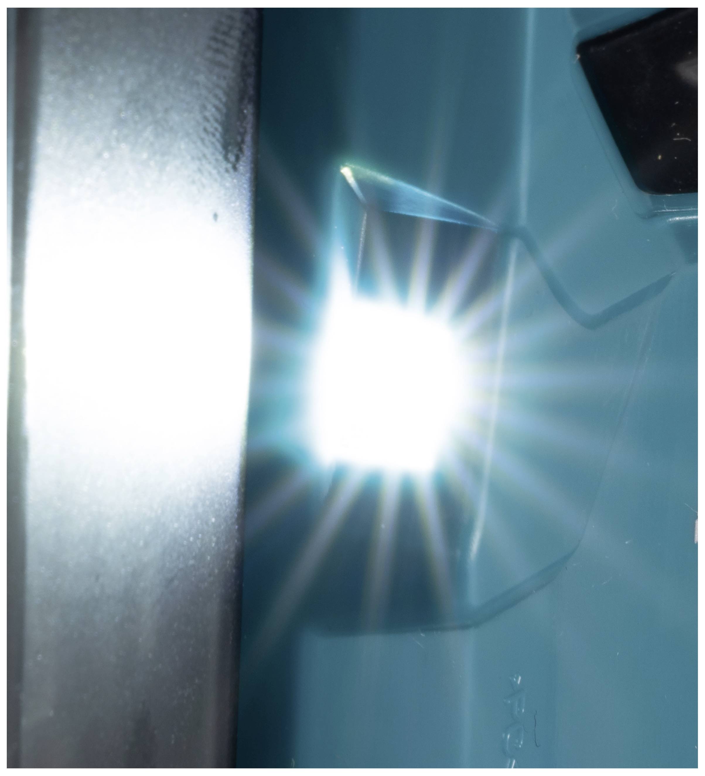 Ein heller Lichtstrahl scheint aus einer kleinen Öffnung auf einem blauen Hintergrund. Links daneben ist eine dunkle Fläche.