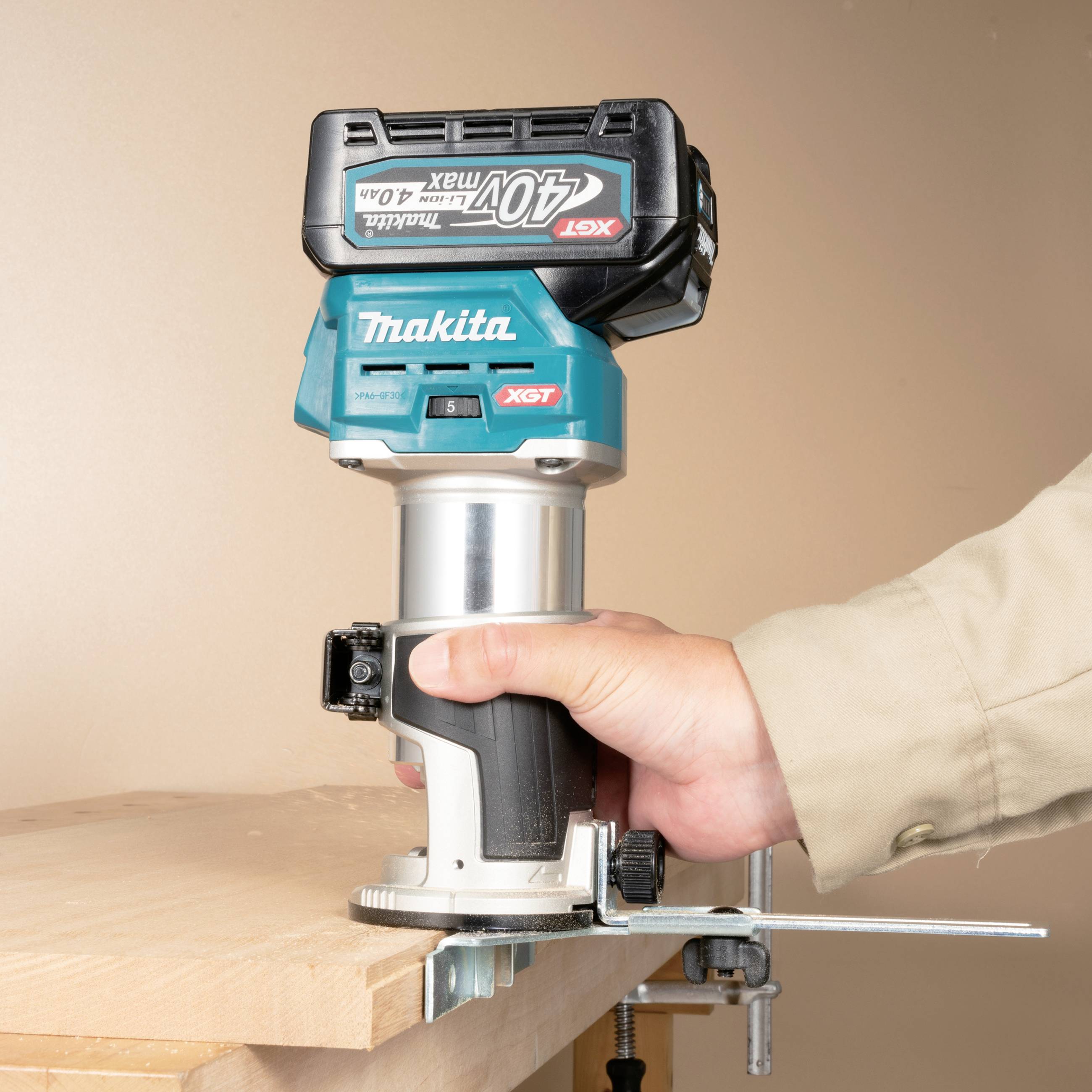 Eine Person hält eine Makita-Holzfräse über einen Holzbalken. Die Fräse hebt sich durch blauen Akzent vom natürlichen Holzton ab.