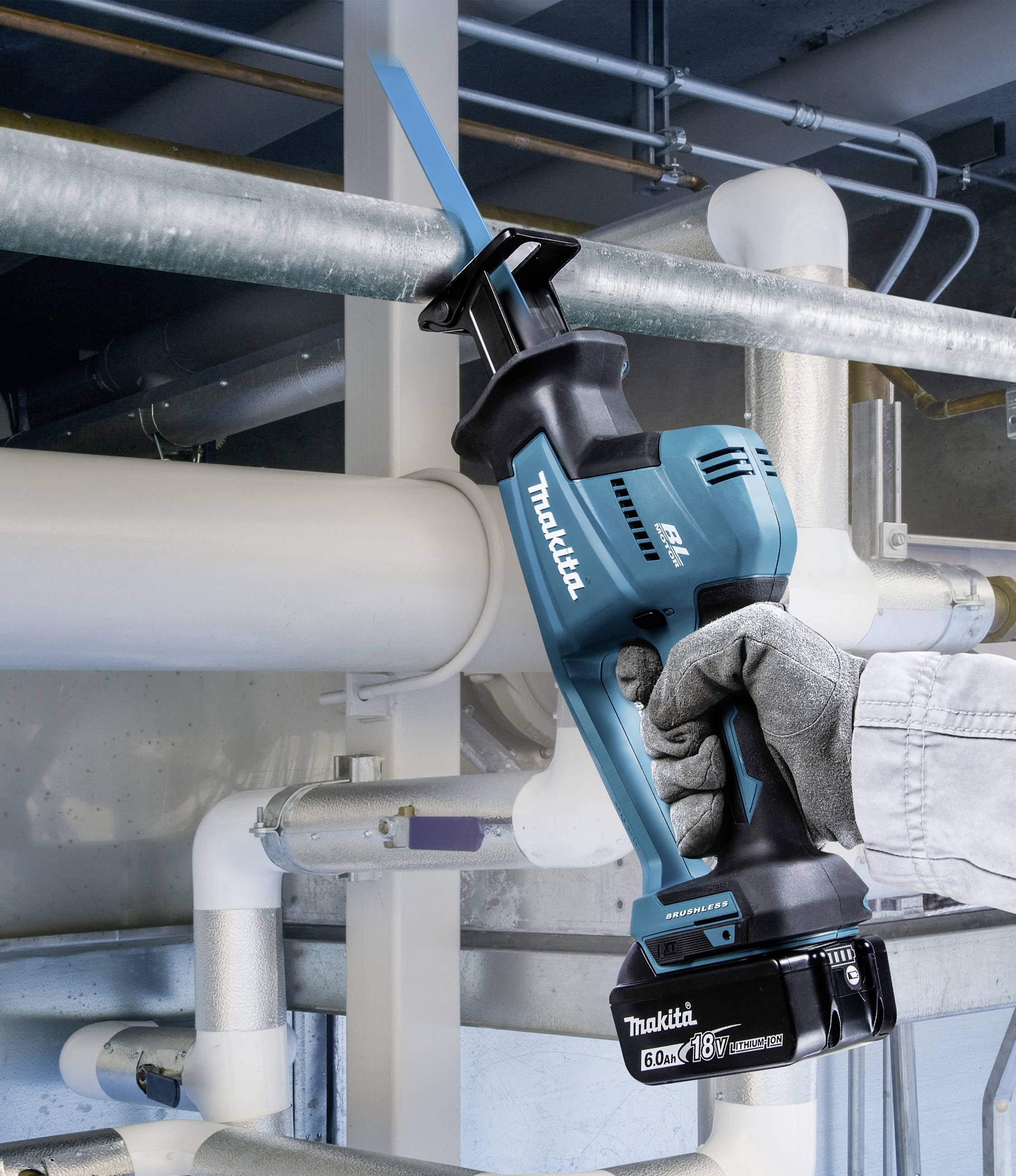 Eine Person verwendet eine blaue Akku-Säbelsäge, um ein Metallrohr zu schneiden. Hintergrund zeigt industrielle Rohrleitungen.